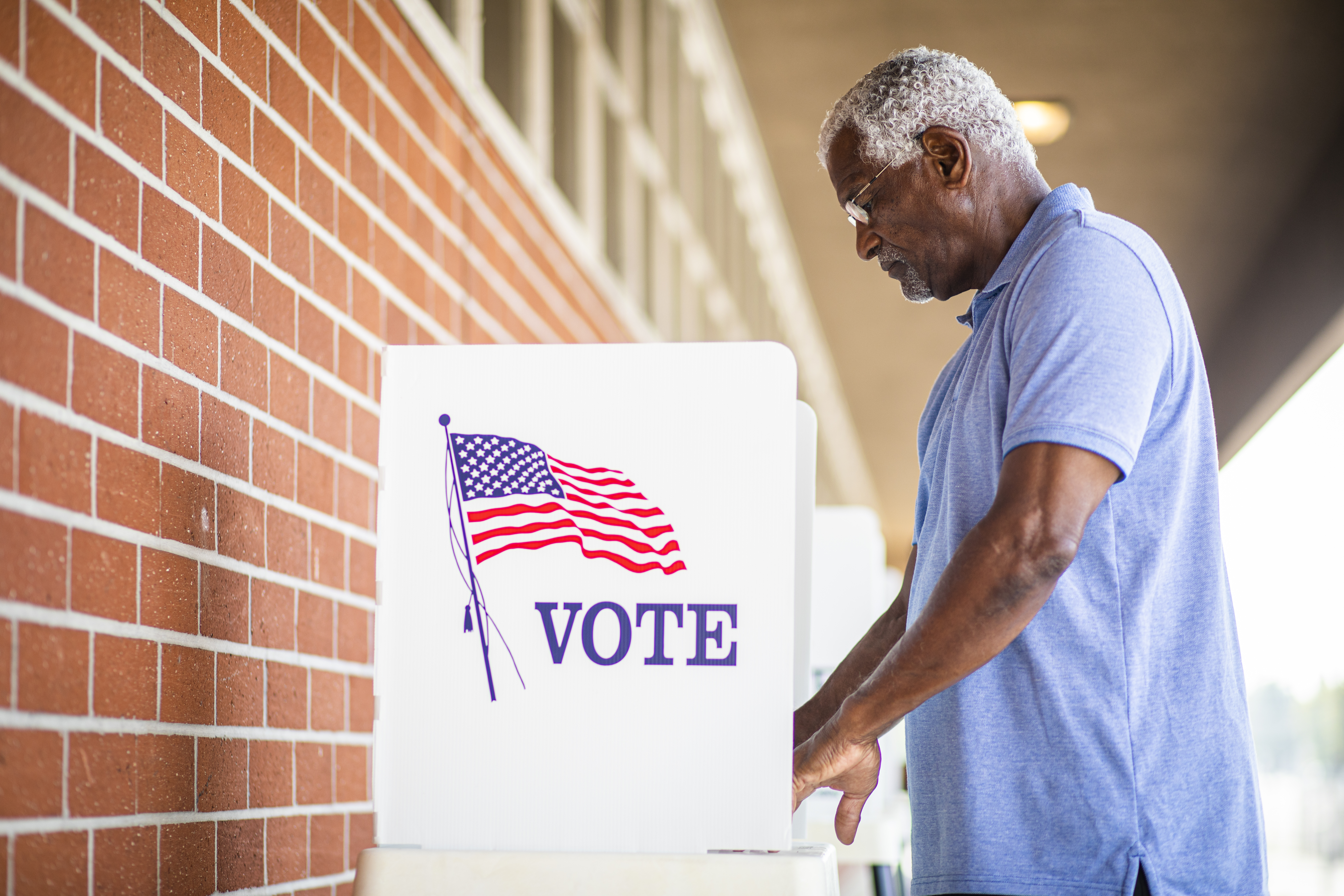 Senior Black Man Voting at Booth