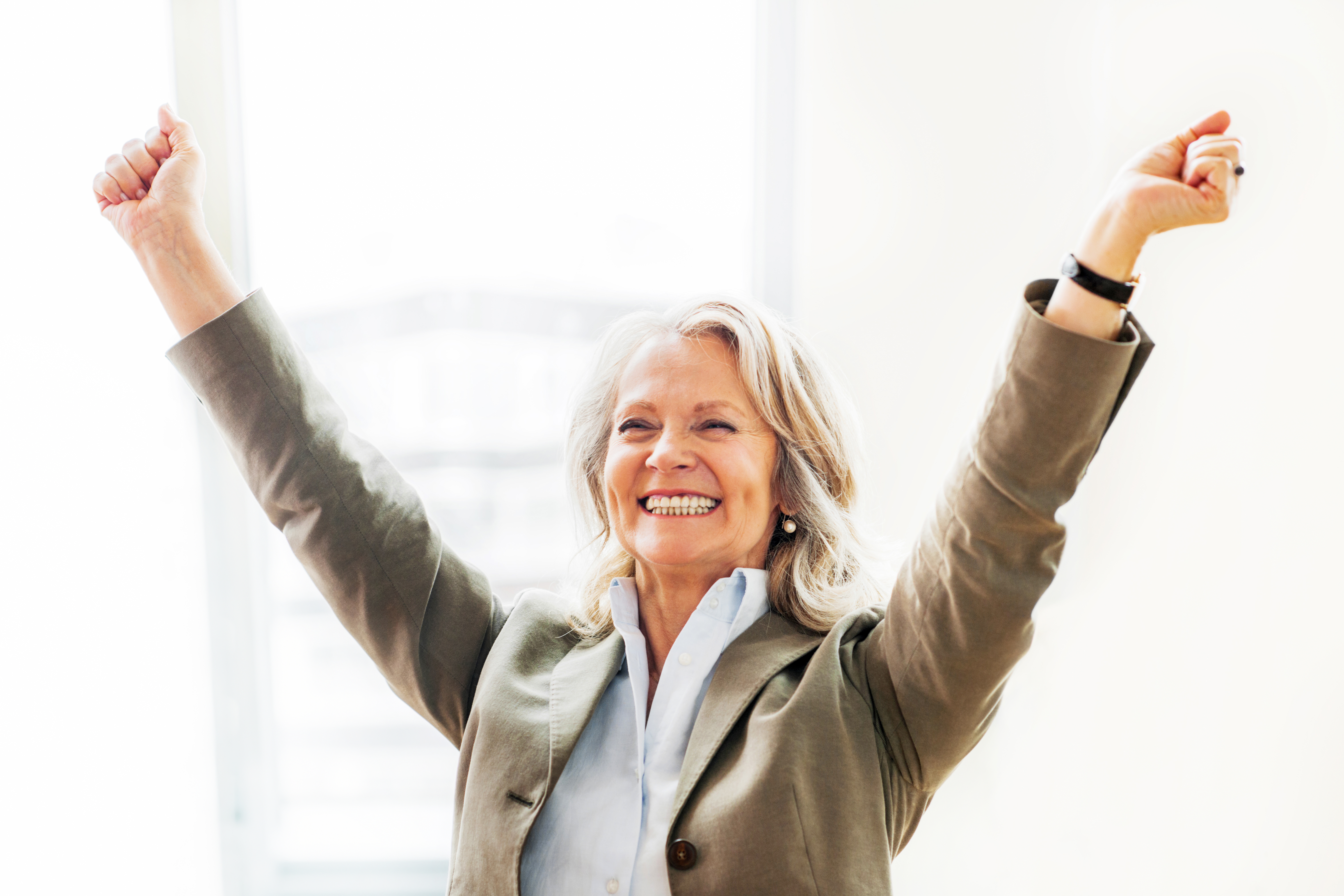 Cheerful mature business woman with raised arms.