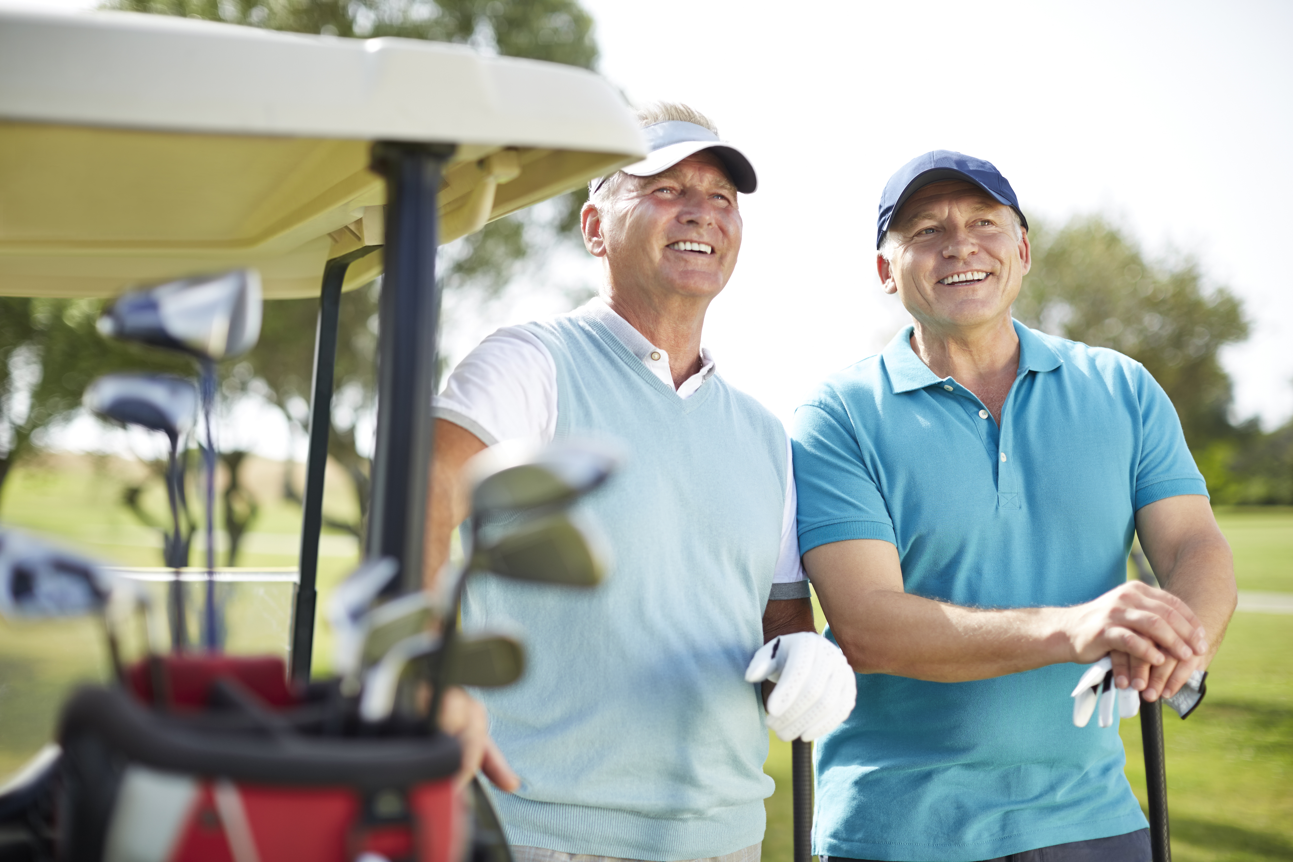 Senior man standing next to golf cart