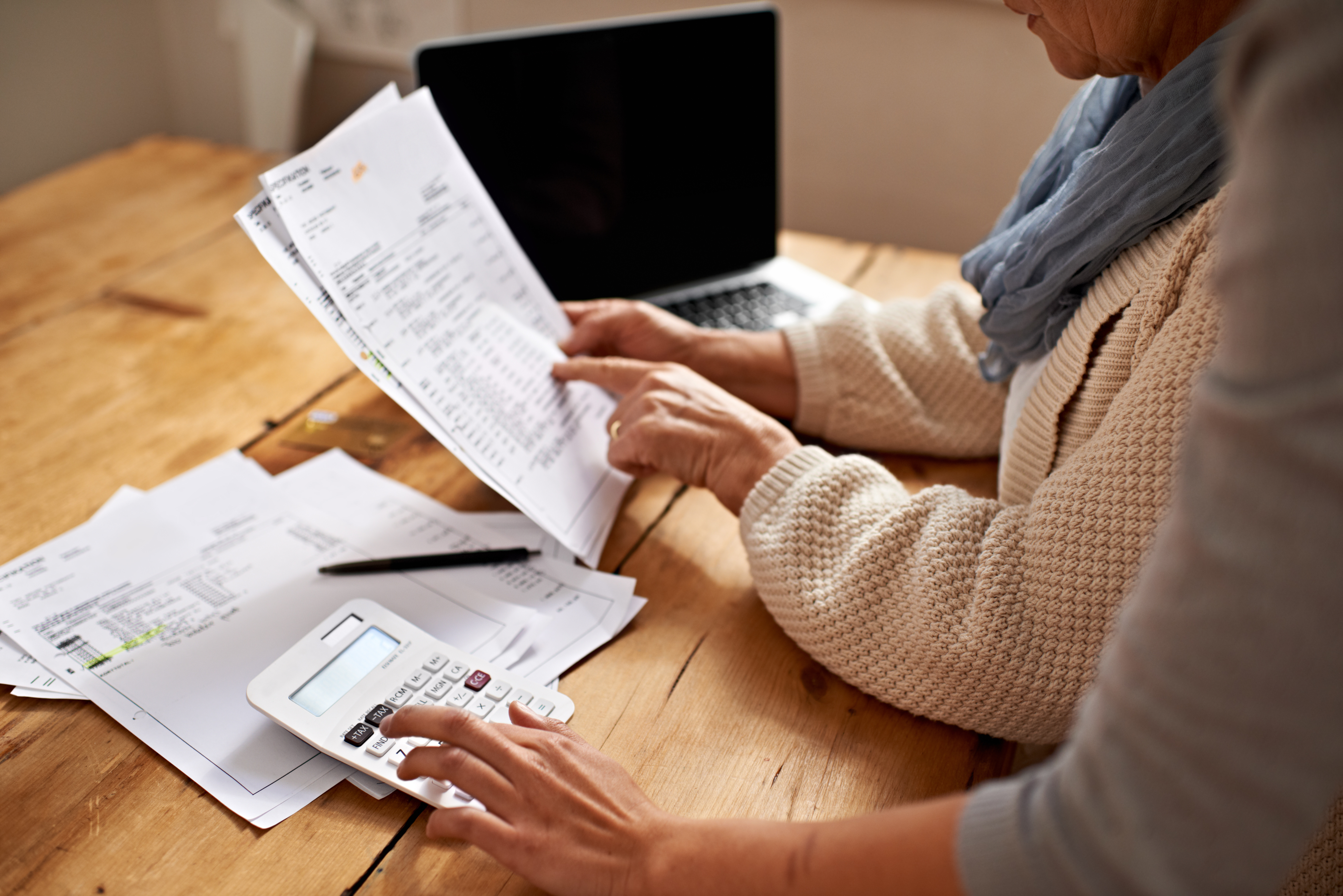 Two women handle financial papers and a calculator