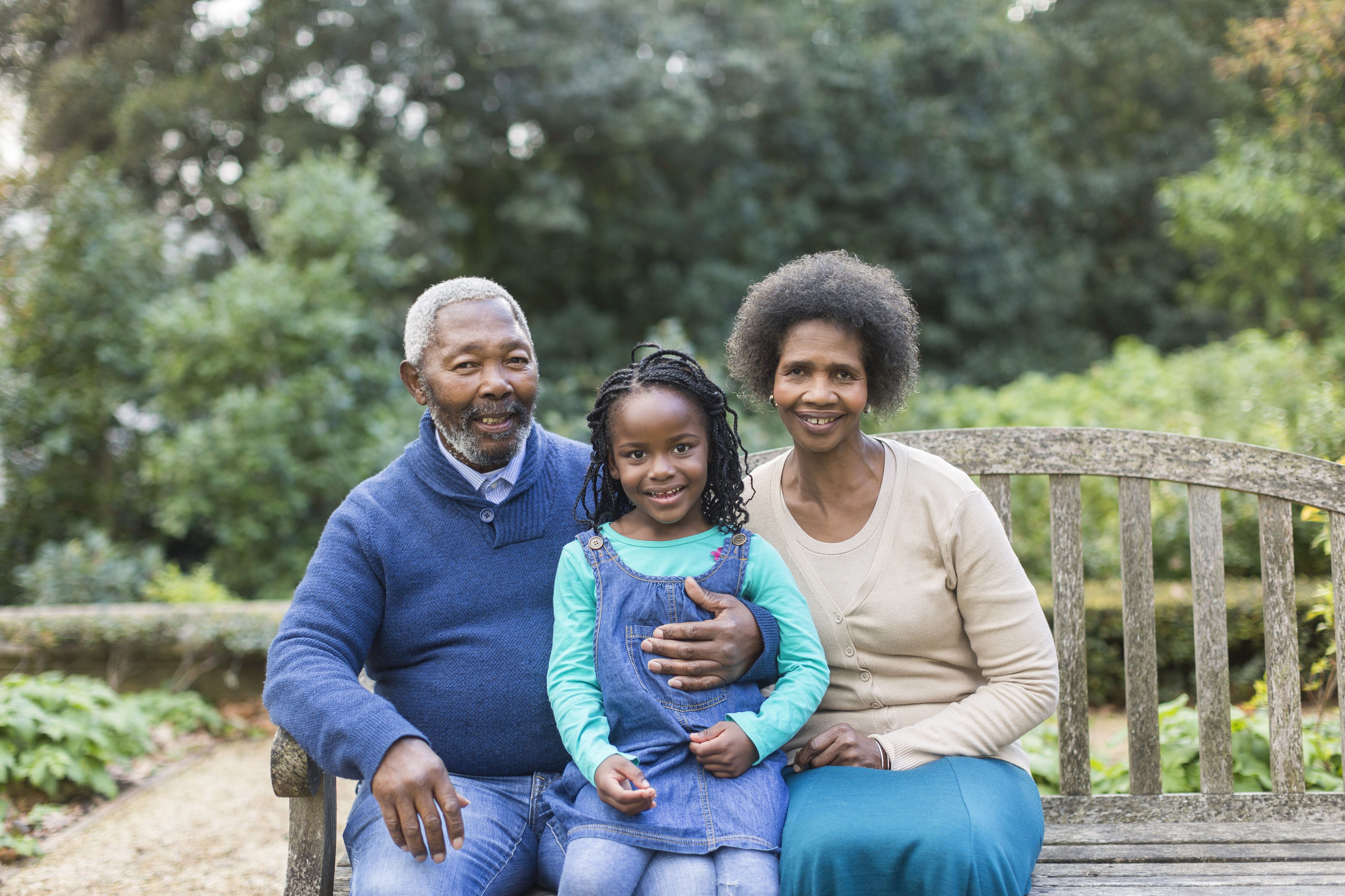 Portrait of grandparents with granddaughter (6-7) on bench in park, Cape Town, South Africa