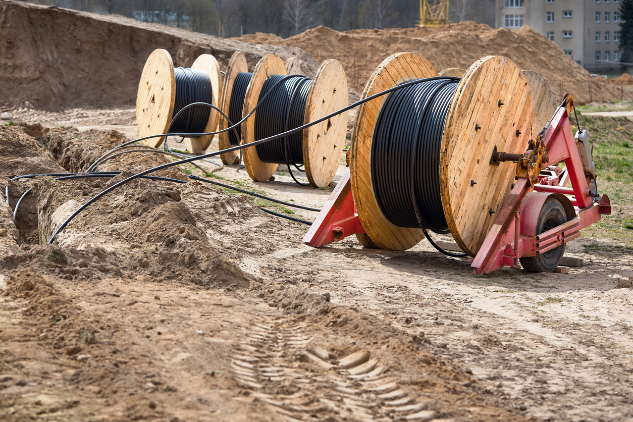 Photo courtesy of RYosha (https://www.istockphoto.com/photo/several-wooden-coils-with-power-cable-laid-in-trench-concept-of-electricity-supply-gm1224891211-360346554)