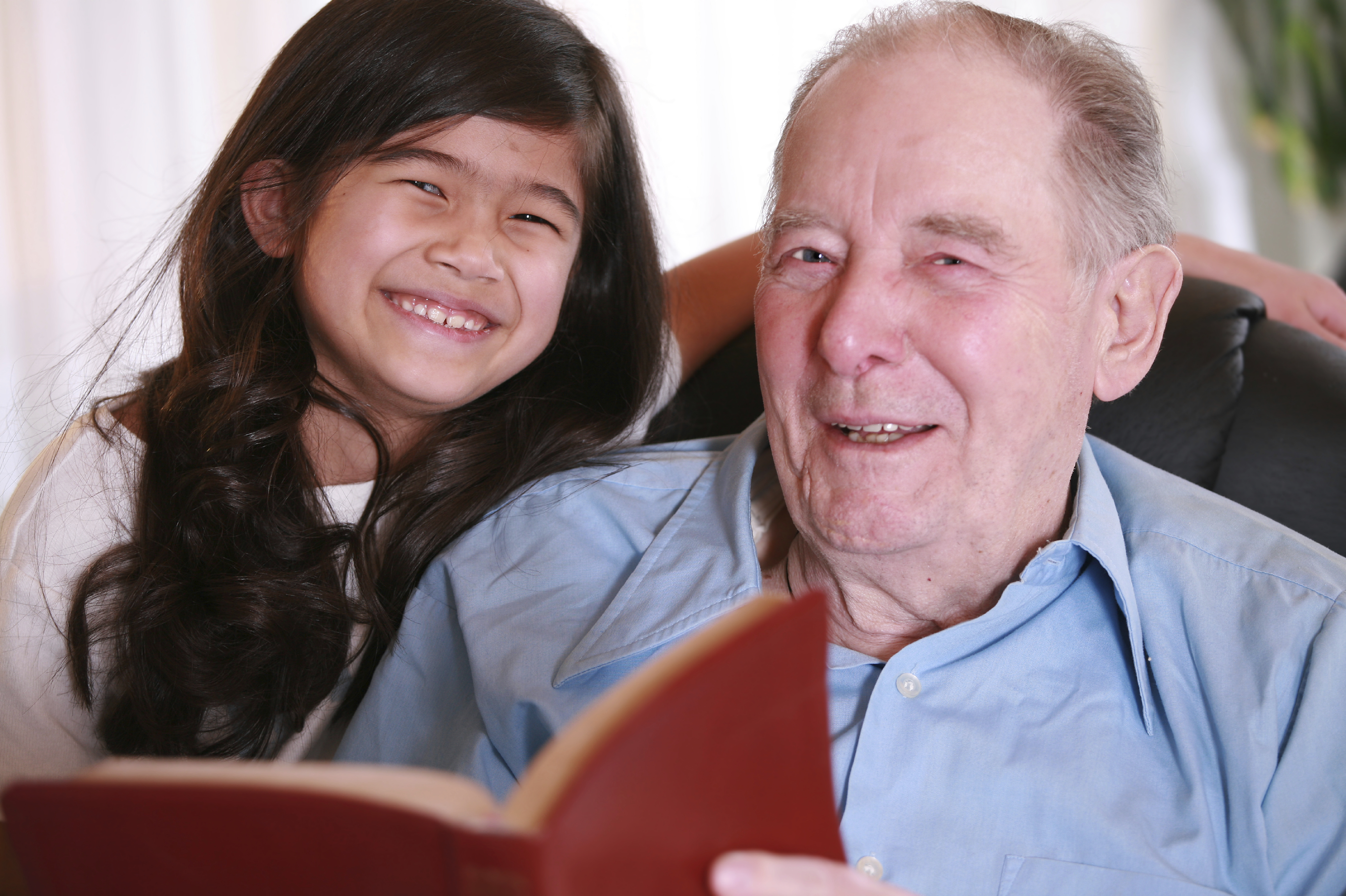 Elderly man and little girl reading Bible together