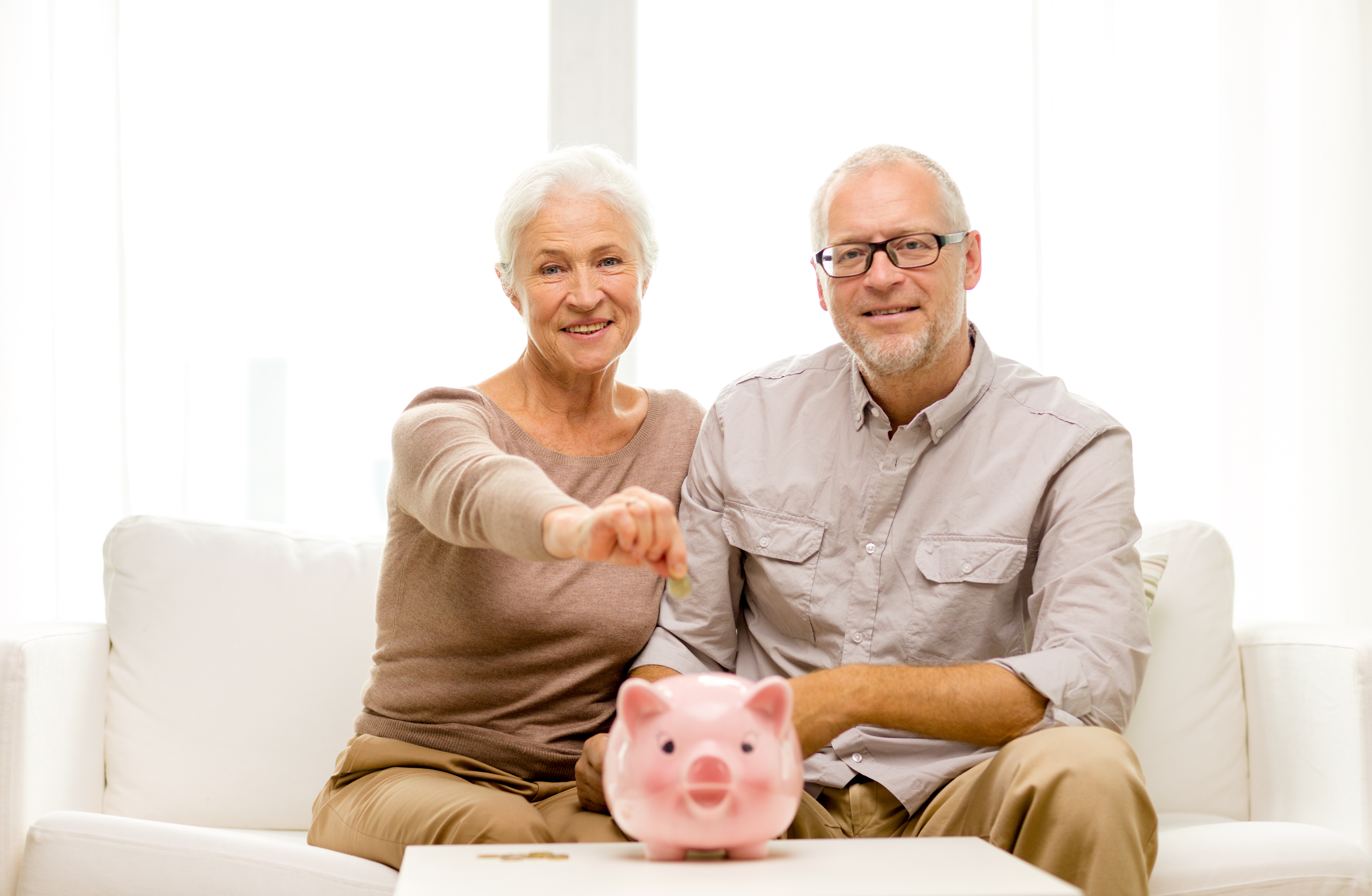 senior couple with money and piggy bank at home