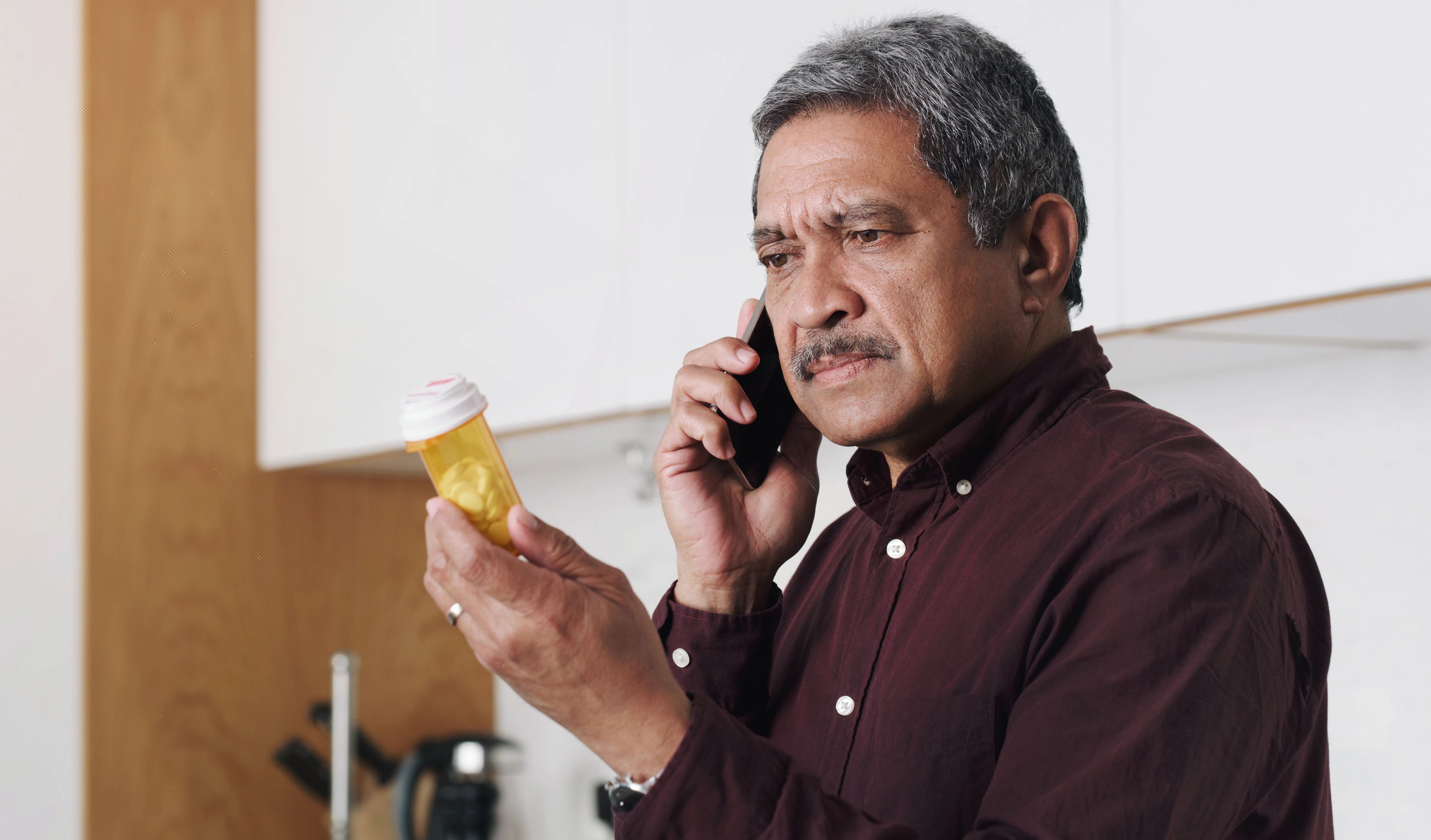 Latino Man Sitting At Table Sorting Through Prescrption Medications