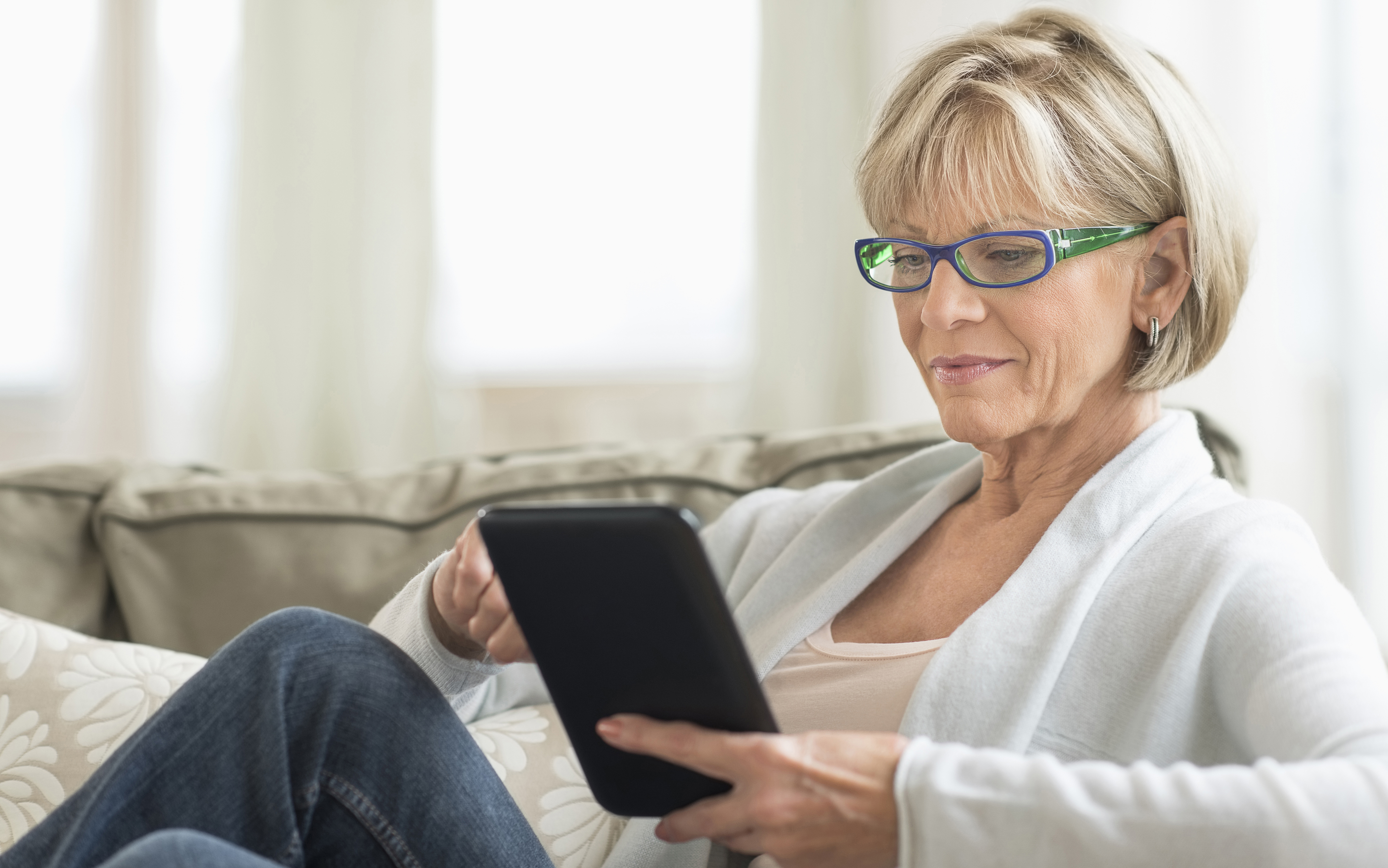 Woman Using Tablet Computer On Sofa