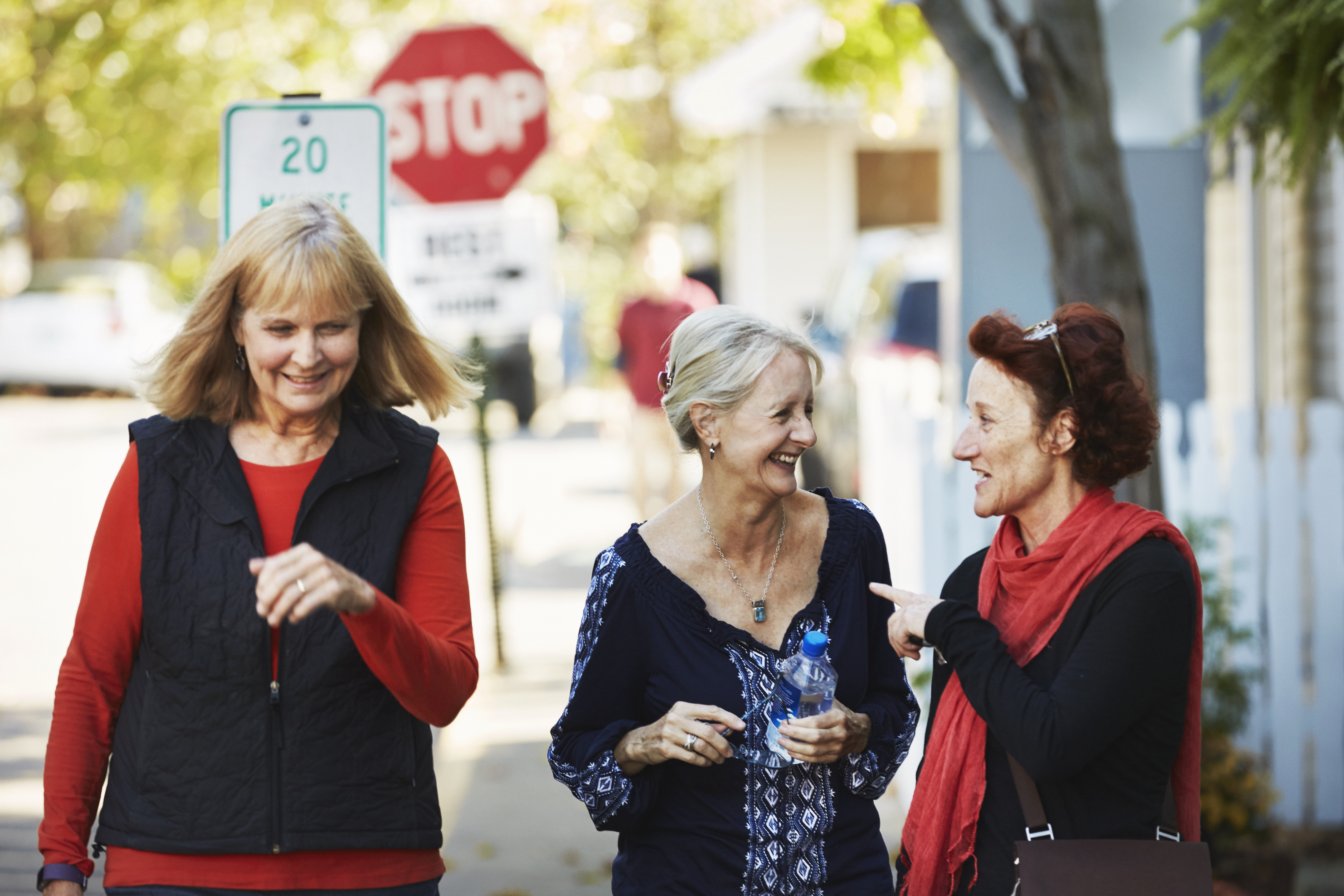 Three senior women walk down the street and talk