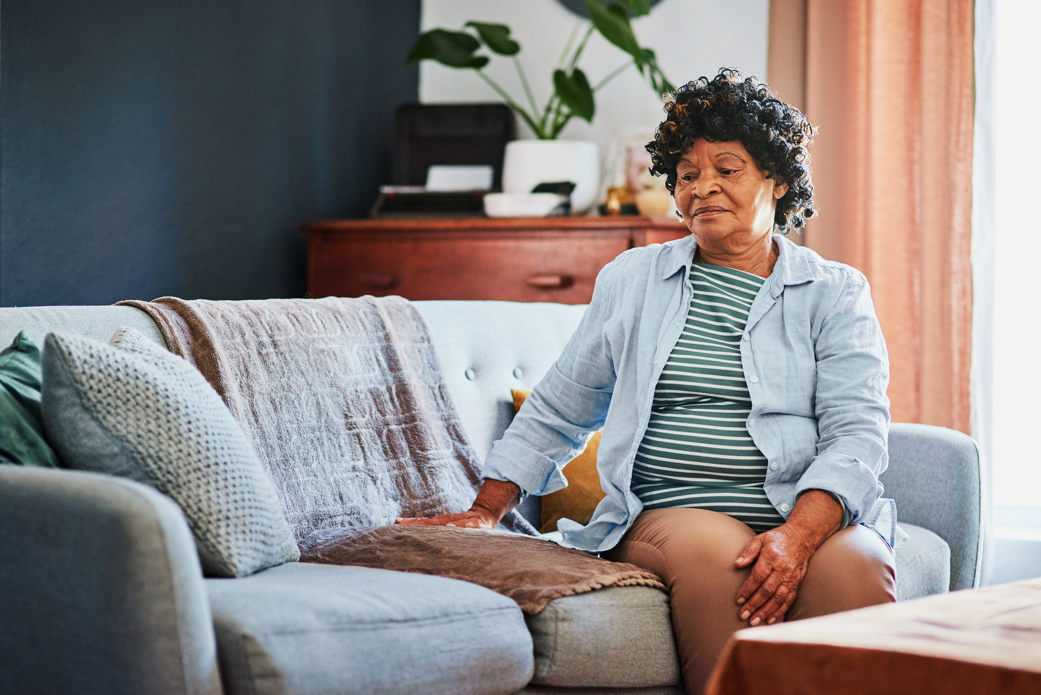 Shot of an elderly woman looking unhappy on the sofa at home