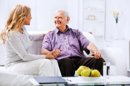 Home caregiver sitting n the sofa with an elderly man.