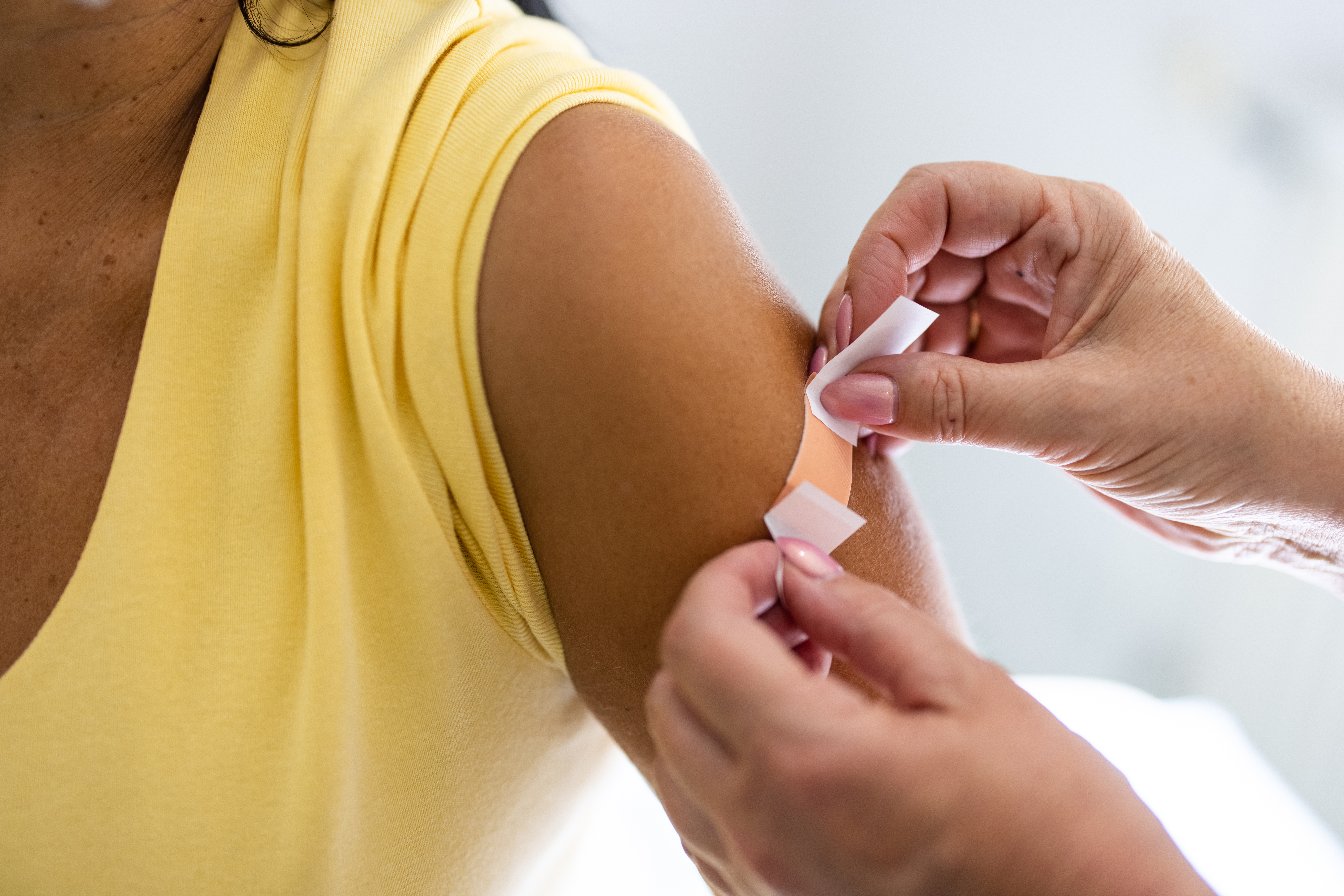 Doctor puts band-aid on woman's arm after administering a COVID-19 vaccine.