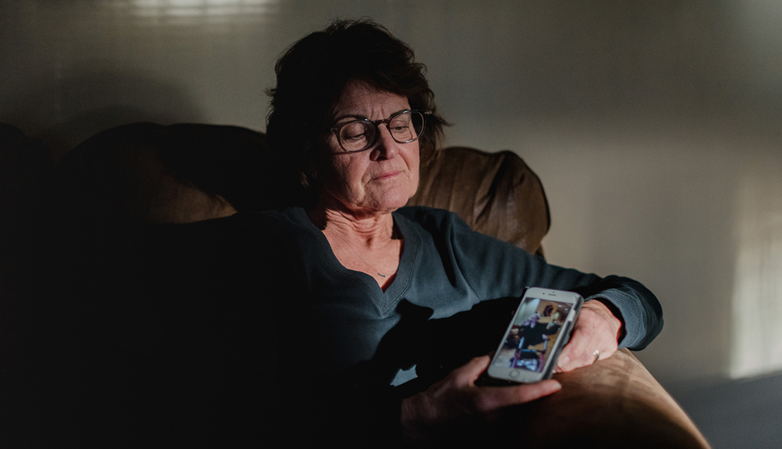 A woman sits in a chair holding a cell phone