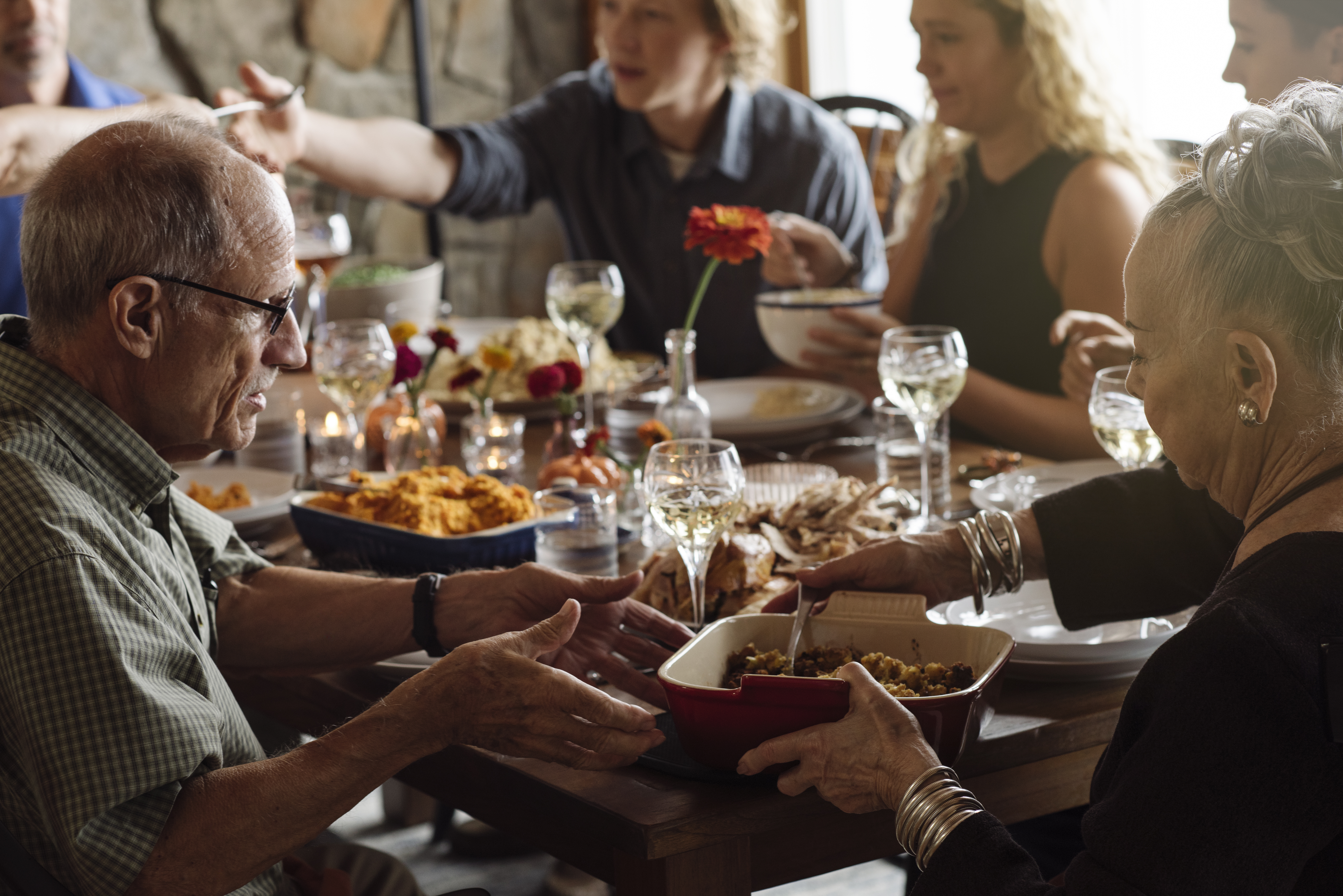 Senior man and woman sharing food while sitting at Thanksgiving dinner