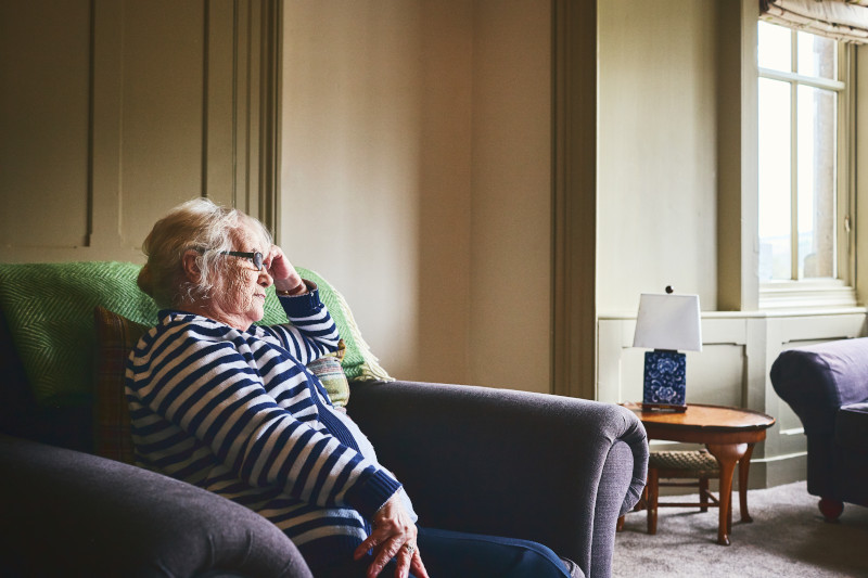 Senior woman sitting alone at home