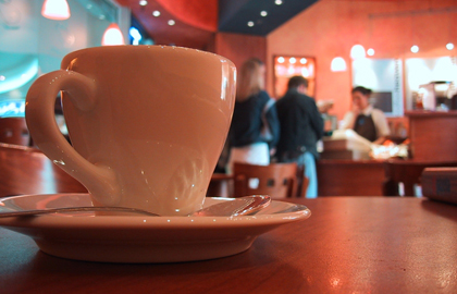 cup of coffee sitting on a table in the foreground with a group of people in the background