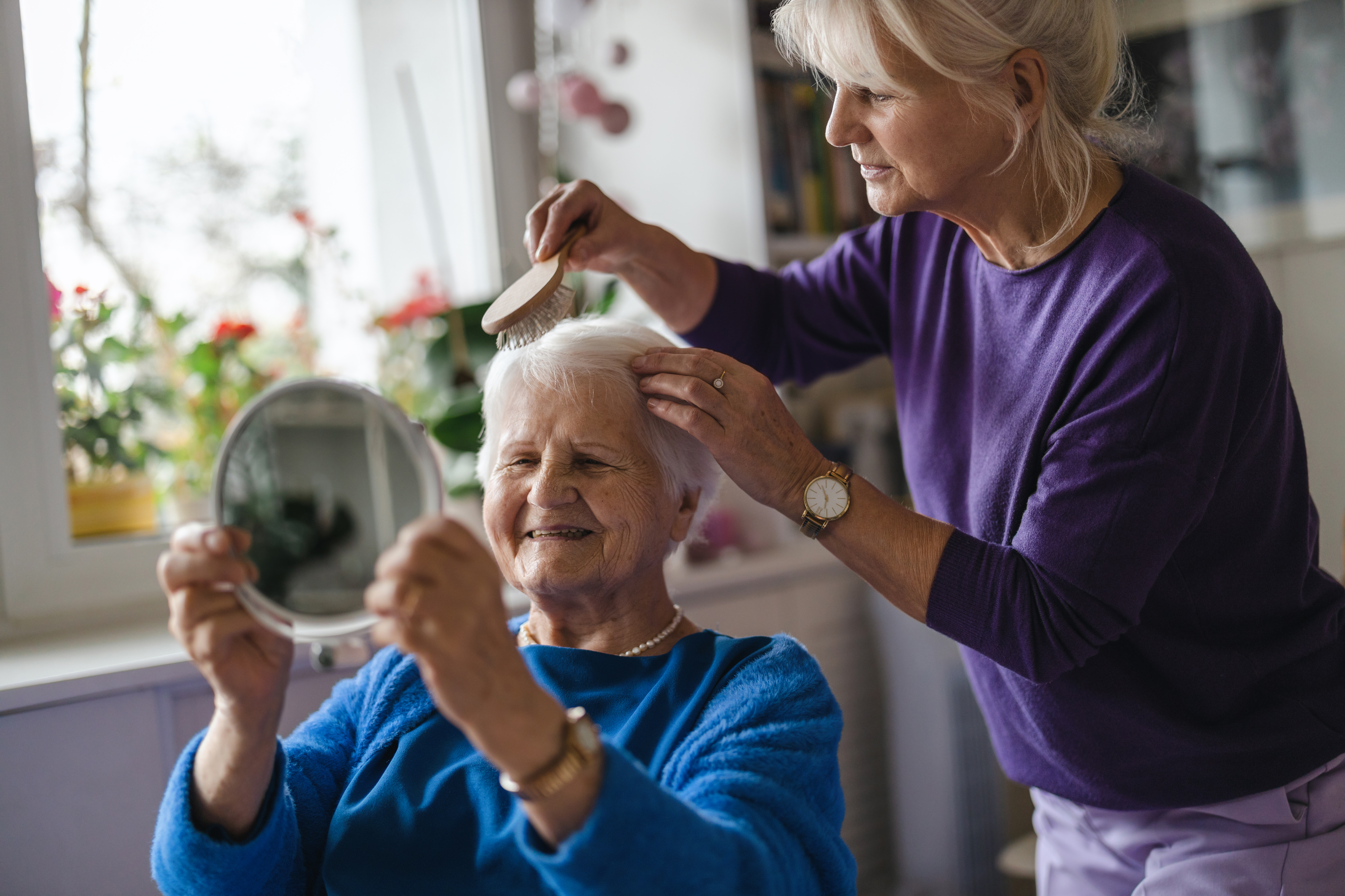 Woman combing hair of elderly mother