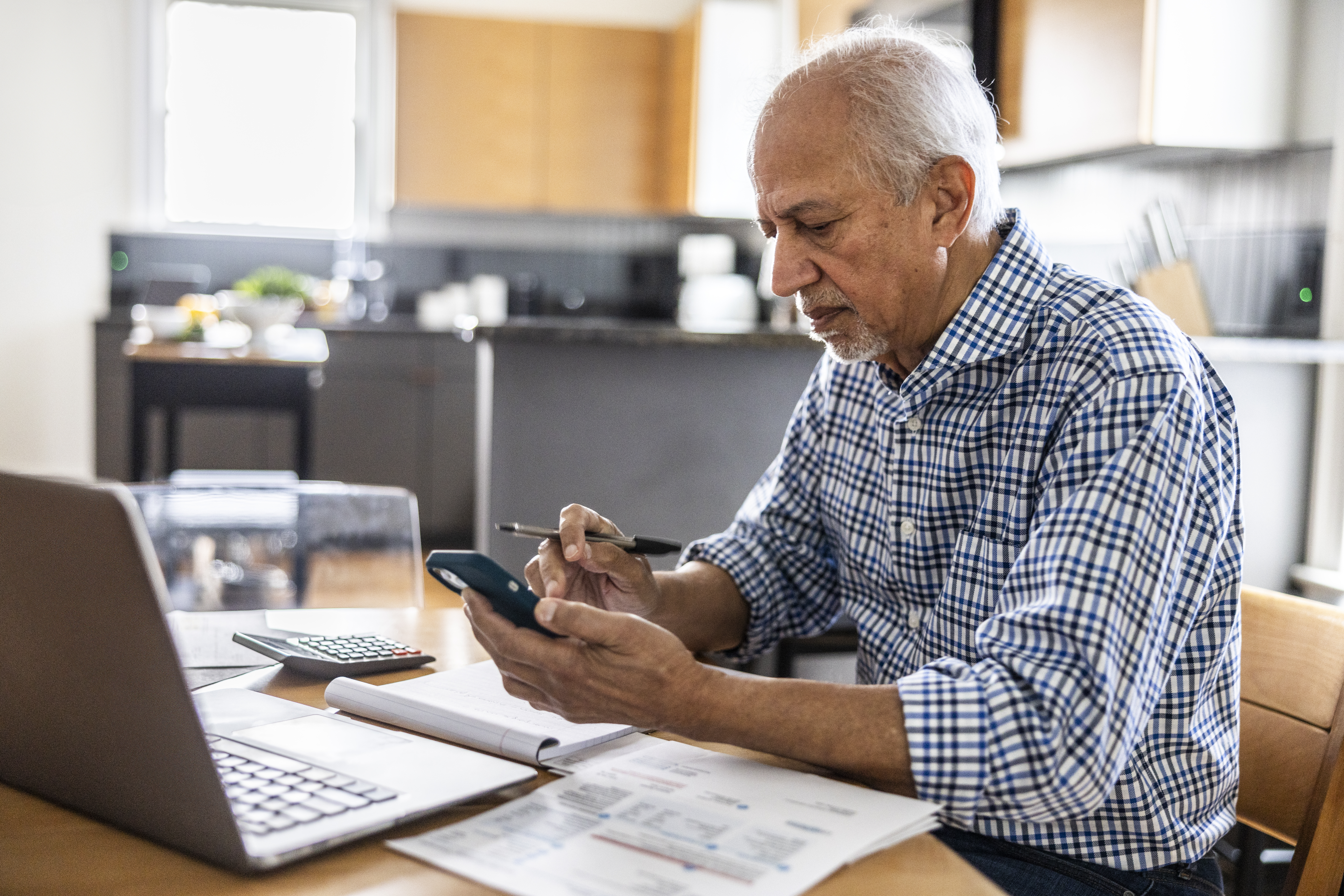 Senior man paying bills at kitchen table
