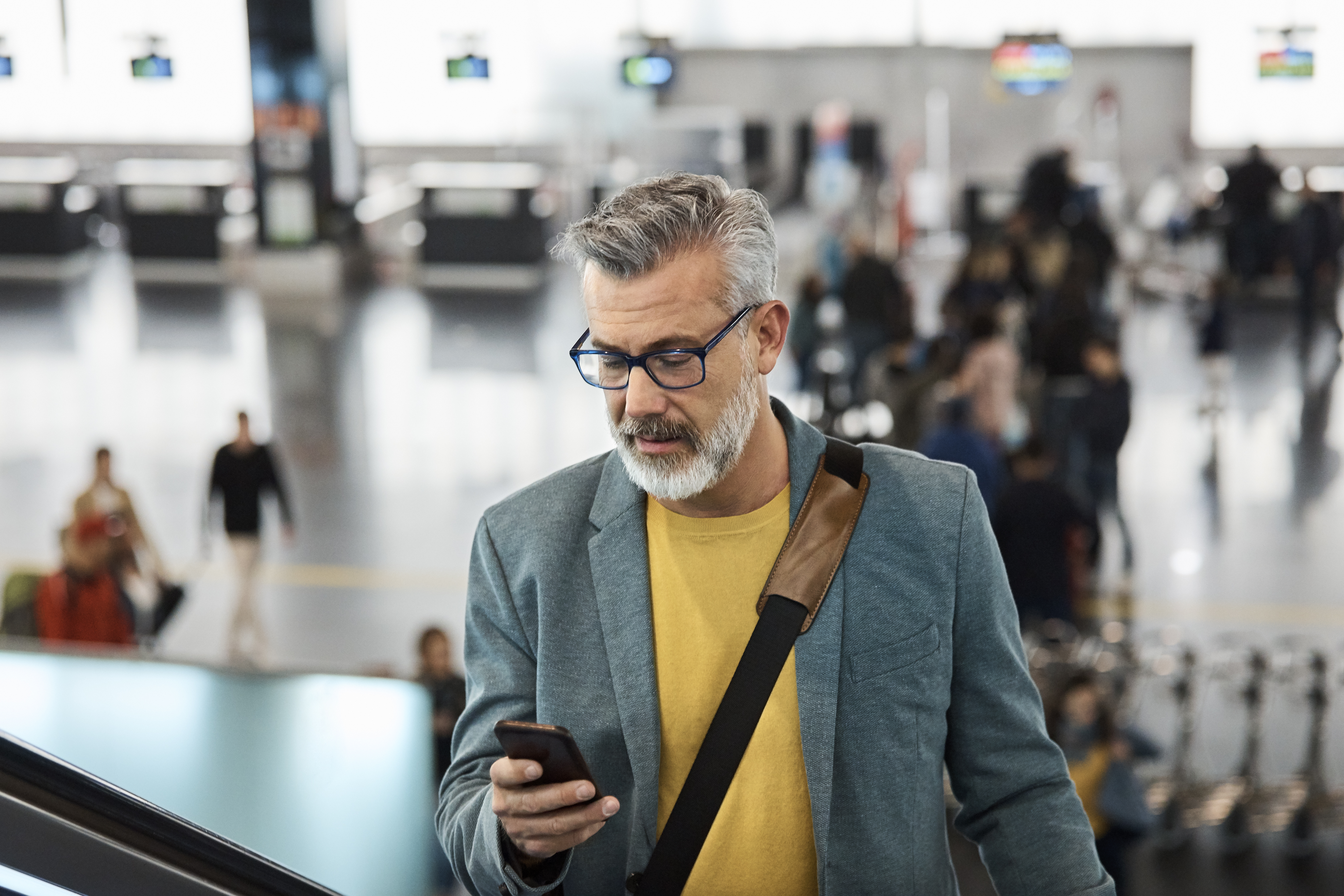 Male commuter using smart phone on escalator