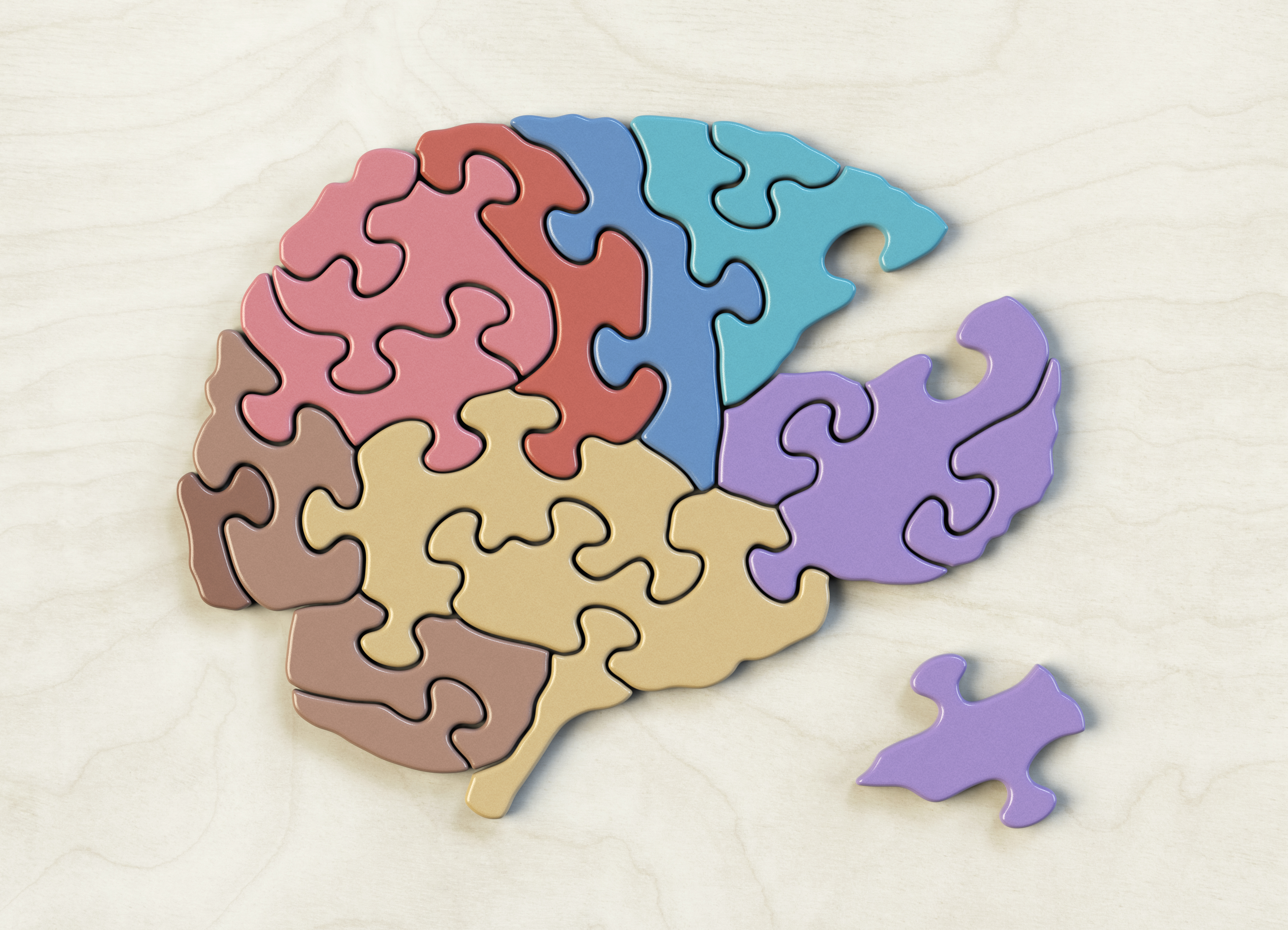 A puzzle shaped like a brain with a single piece missing and off to the side.