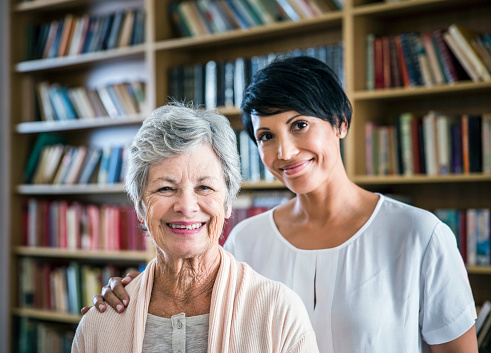 Caretaker with arm around senior woman in library