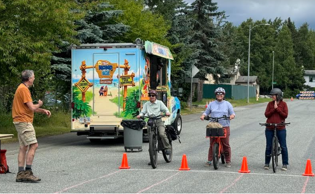 Three bikers line up at a start line marked with traffic cones