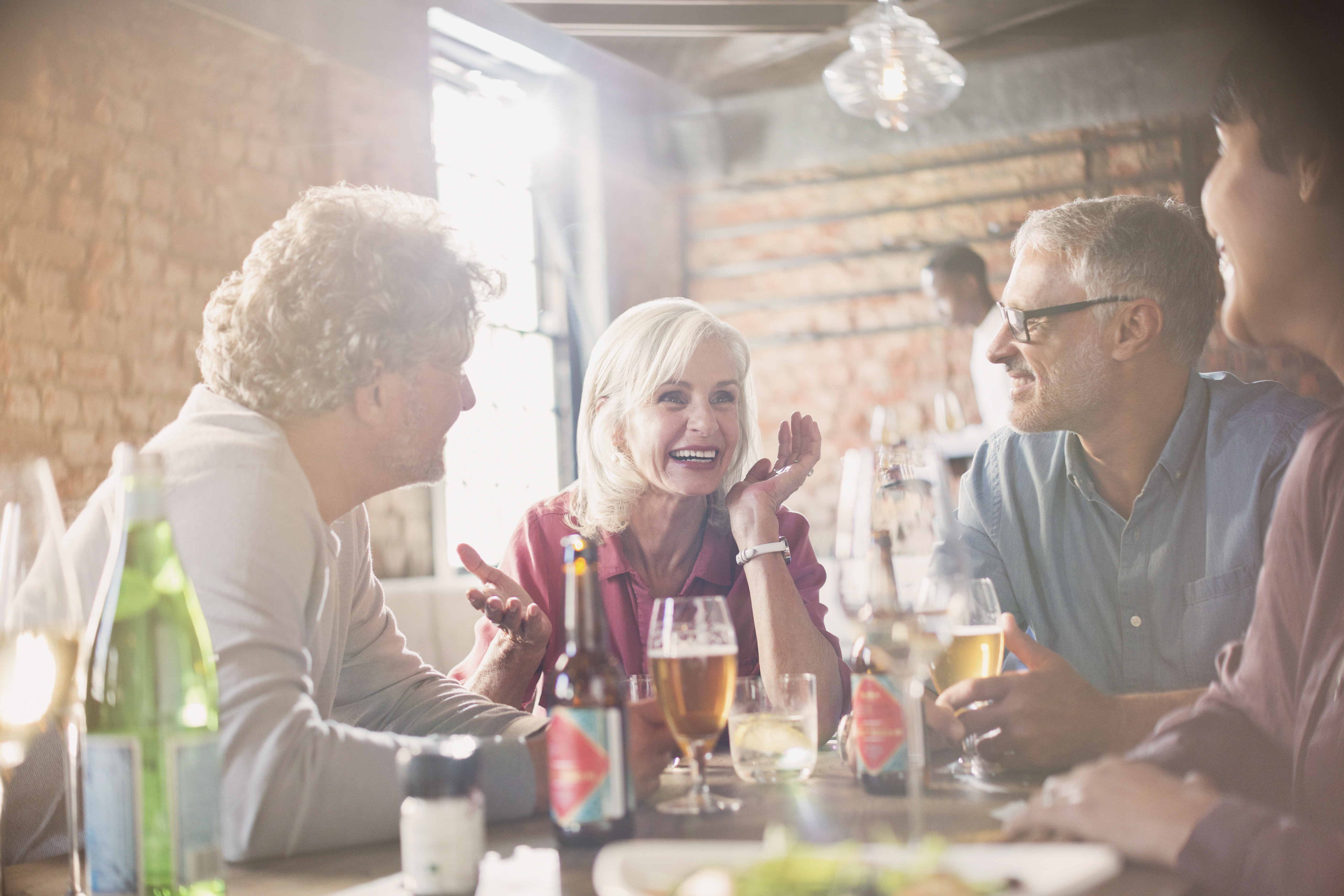 Couples talking and drinking beer at restaurant table