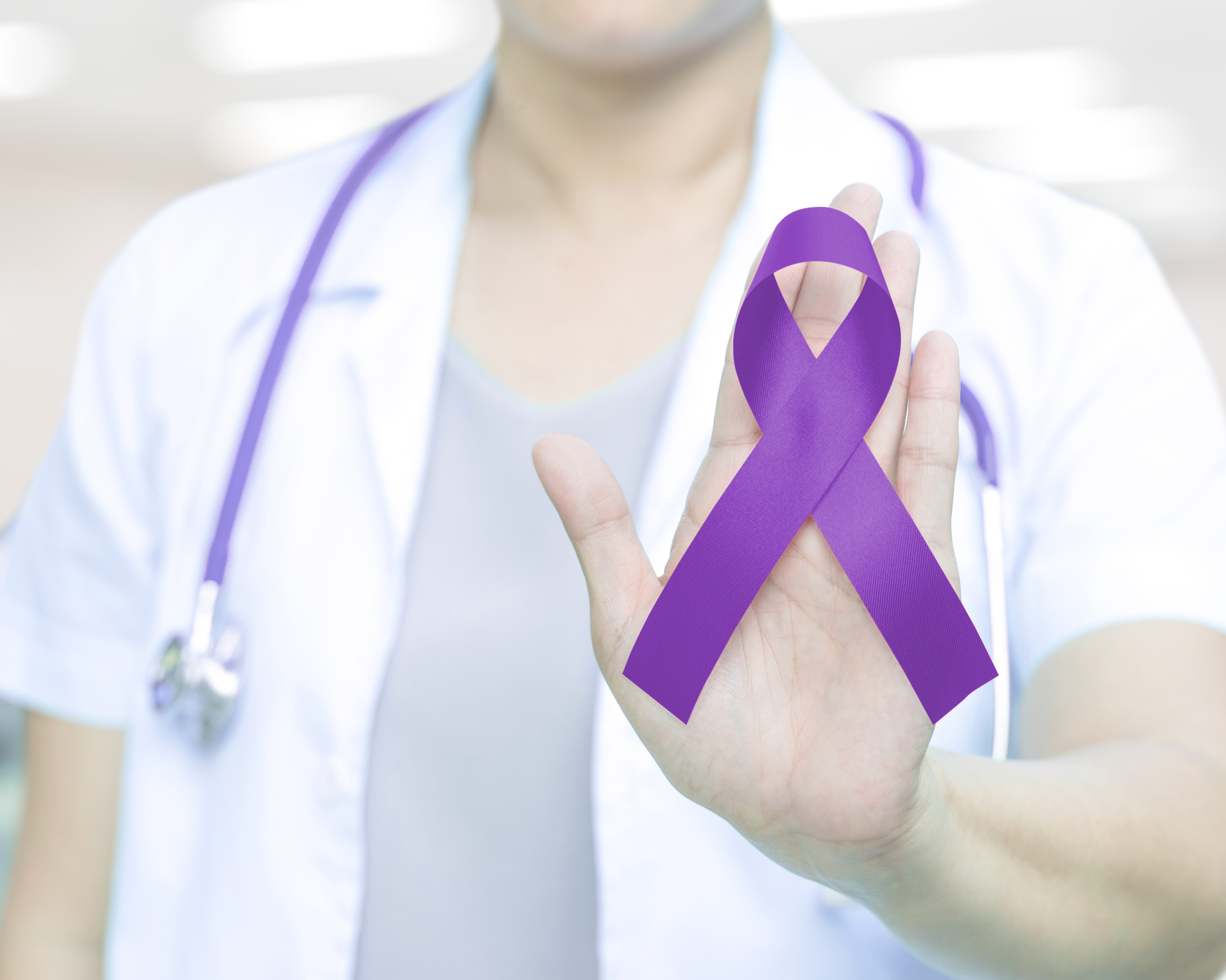 Female doctor in white uniform hold purple violet ribbon awareness in hand.