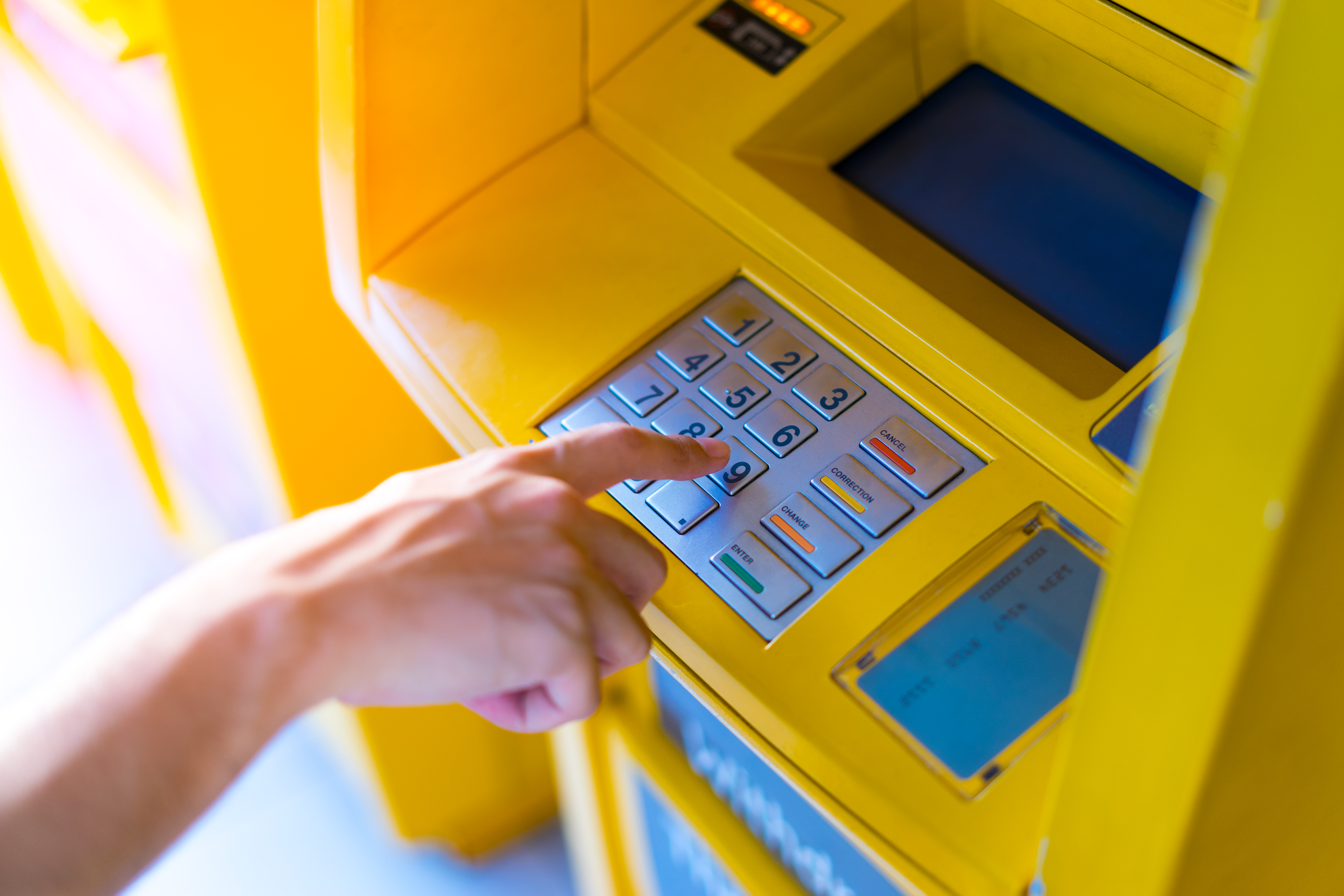 Man hand entering his PIN at an ATM