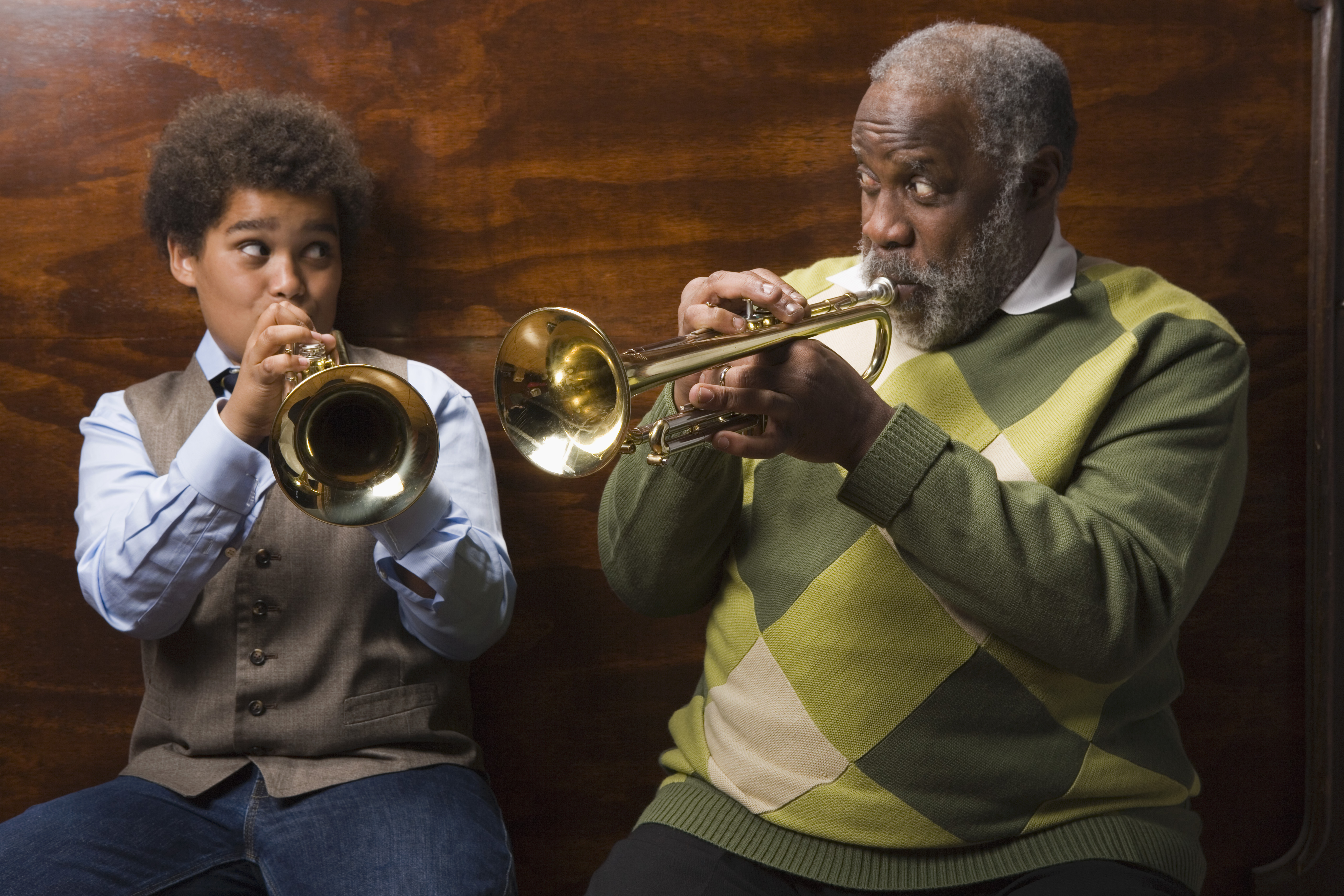 Preteen boy and grandfather playing trumpet together