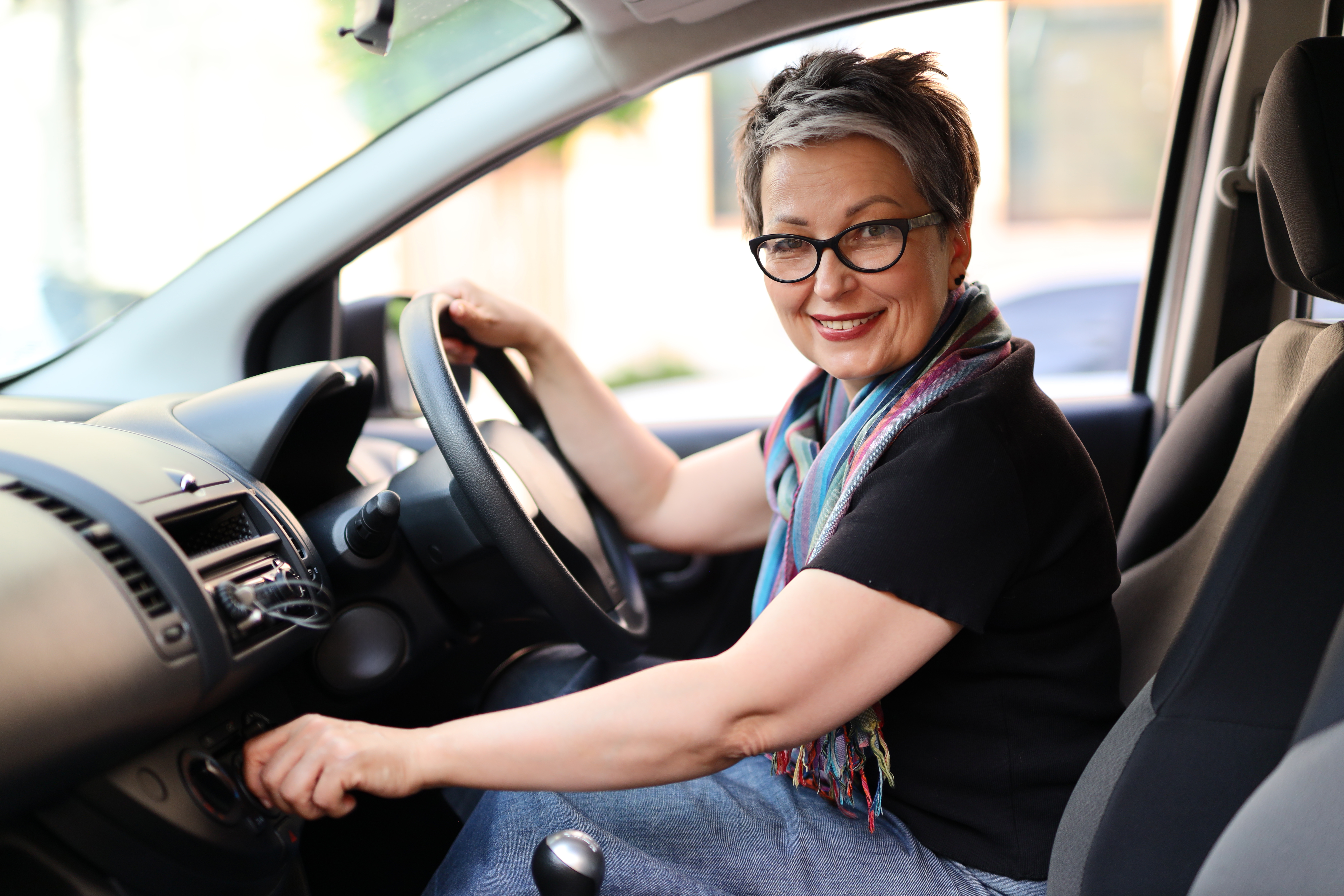 A happy female driver turns on the climate control and prepares to start traveling in a rented car.