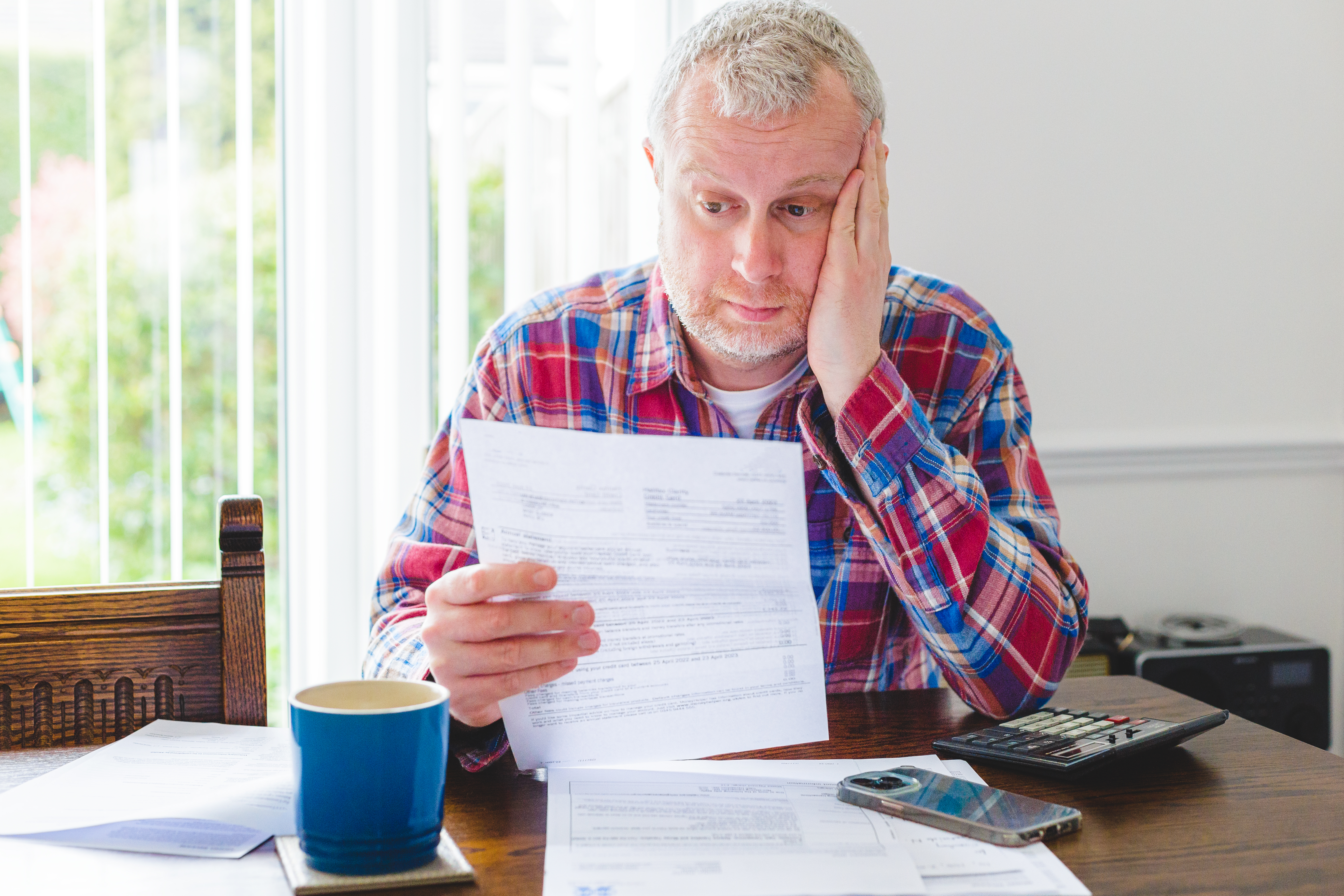 Worried man checking energy bills at home