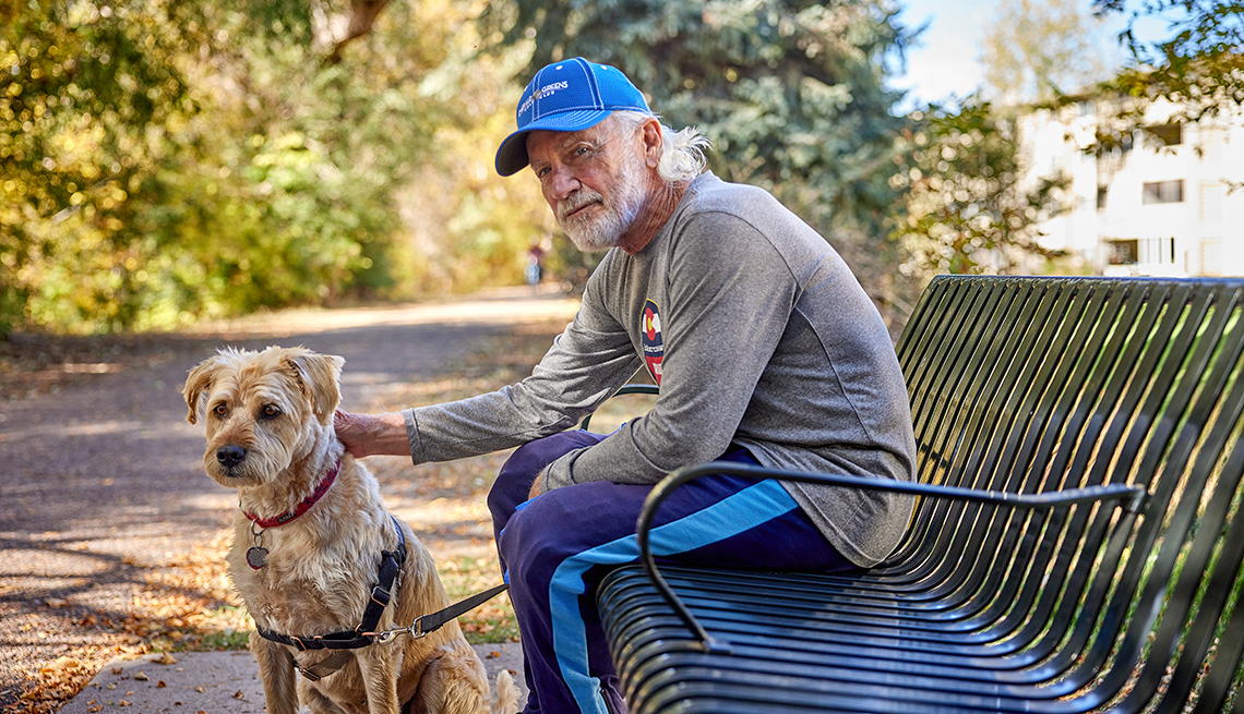 a man sits on a bench with his dog by his side