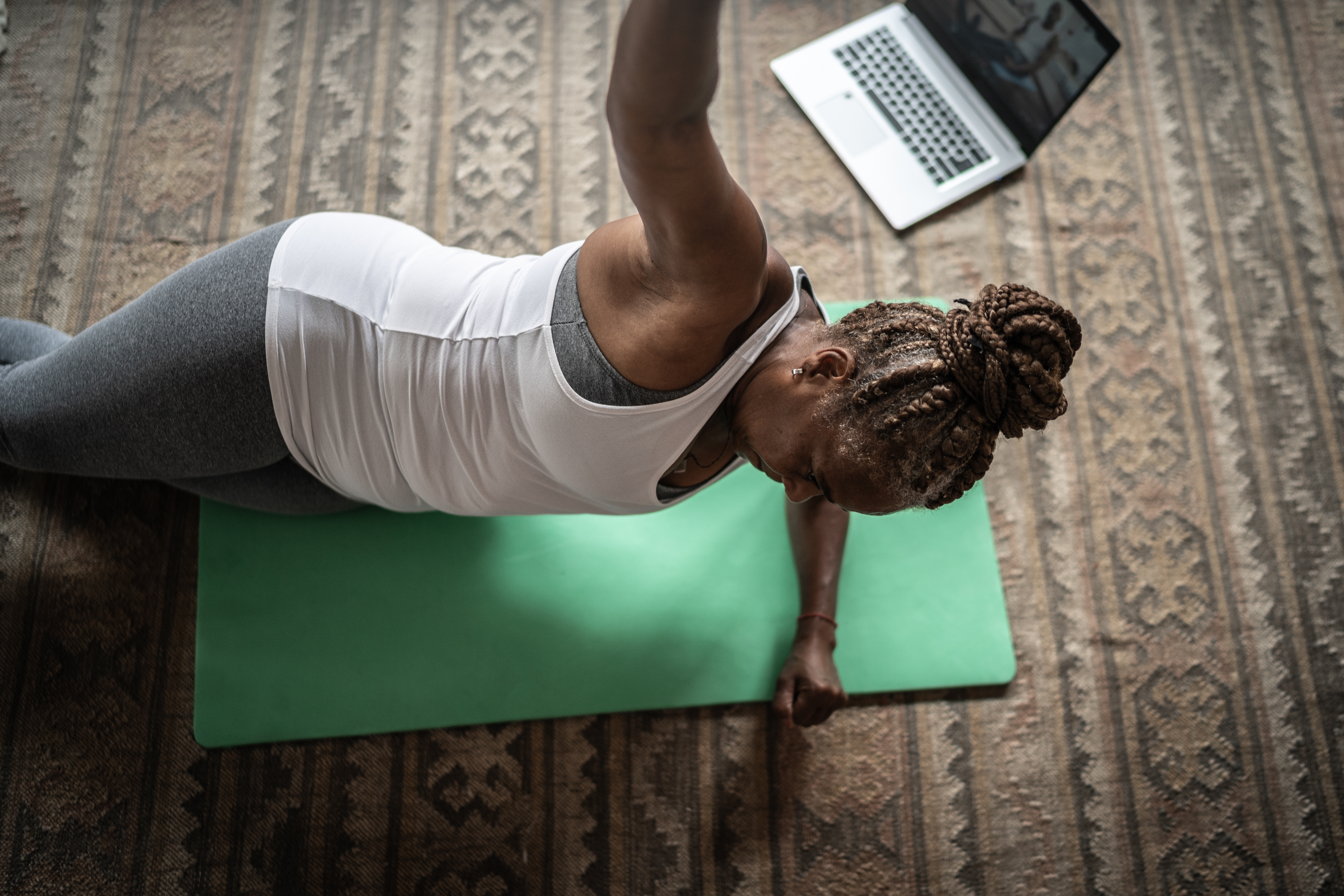 Senior woman doing online exercise class with laptop at home