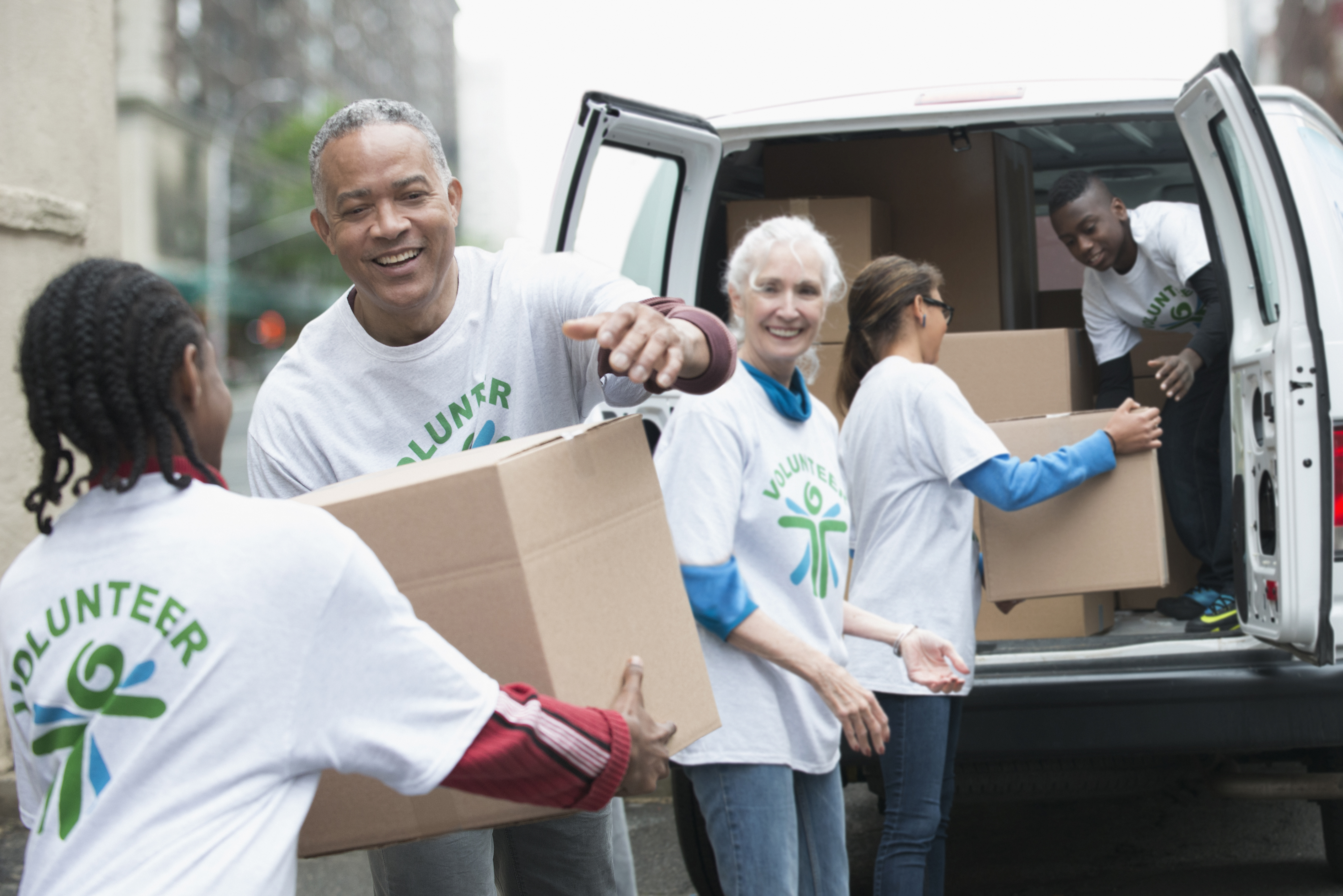 Volunteers passing cardboard boxes from delivery van