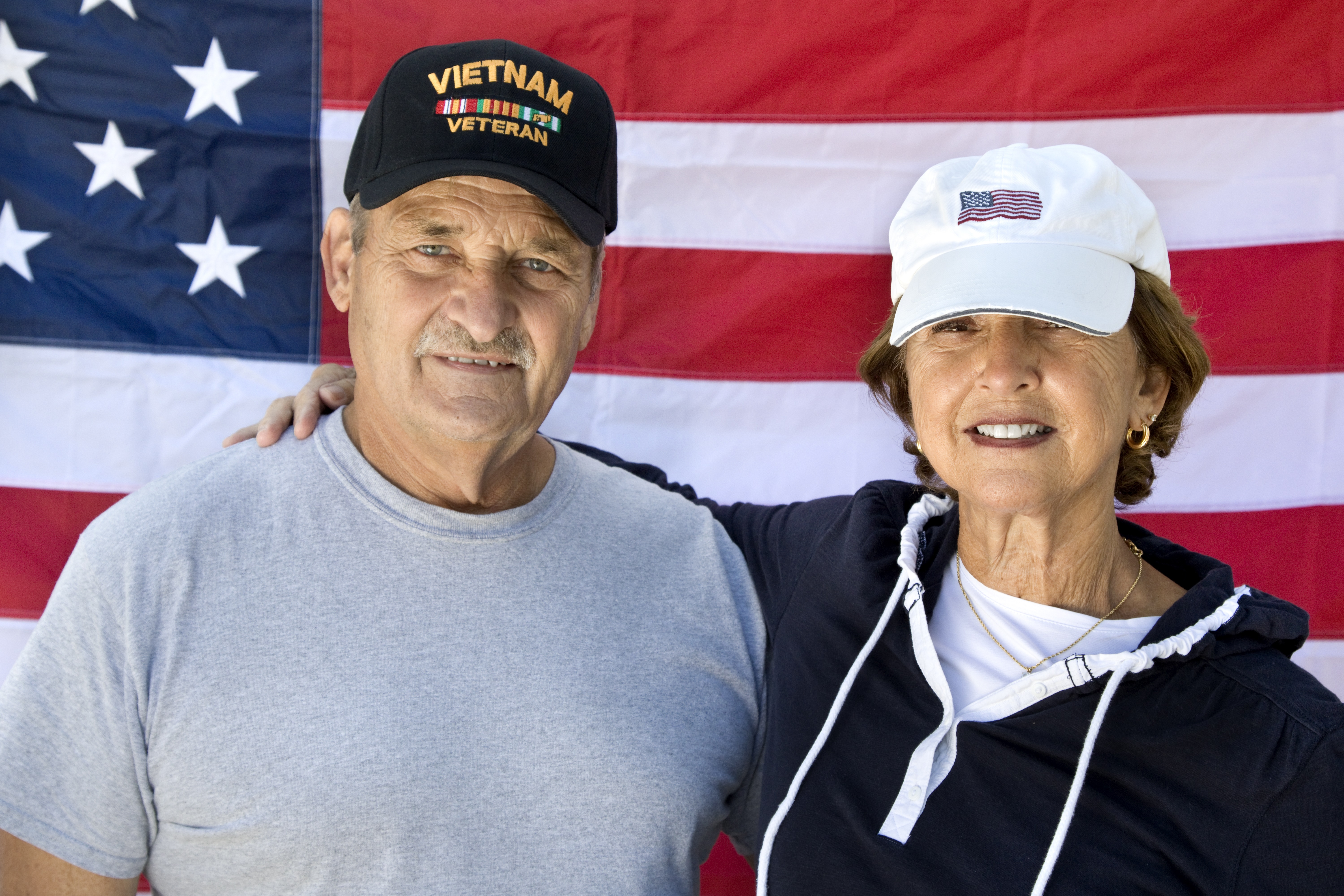Vietnam Veteran and Wife looking at camera with American Flag in background