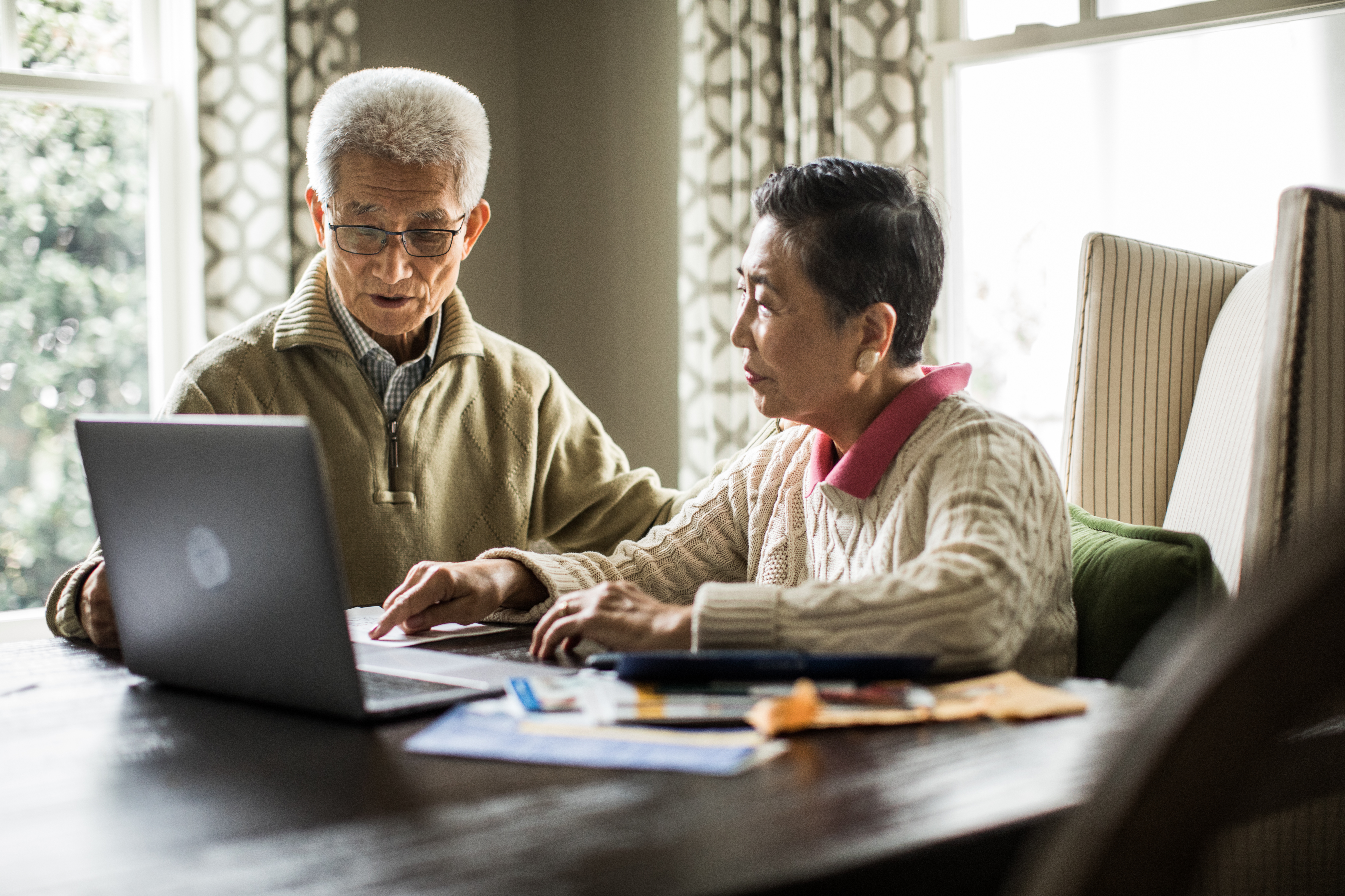 Senior couple using laptop to pay bills at home