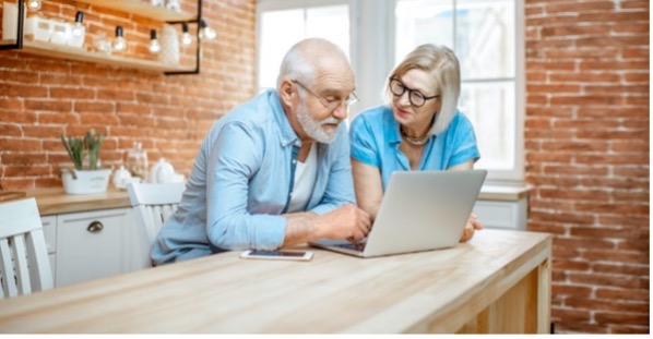 Younger woman helps older man on laptop