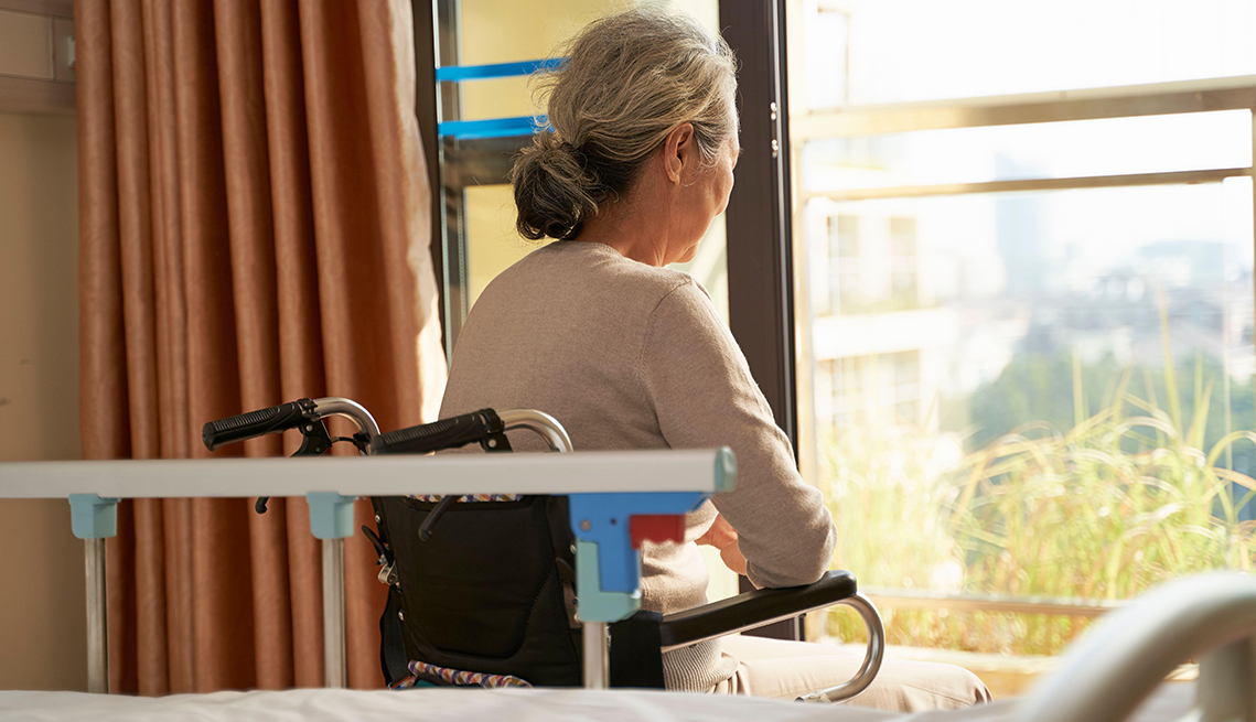 rear view of senior asian woman sitting in wheel chair in nusing home or hospital ward  in front of window