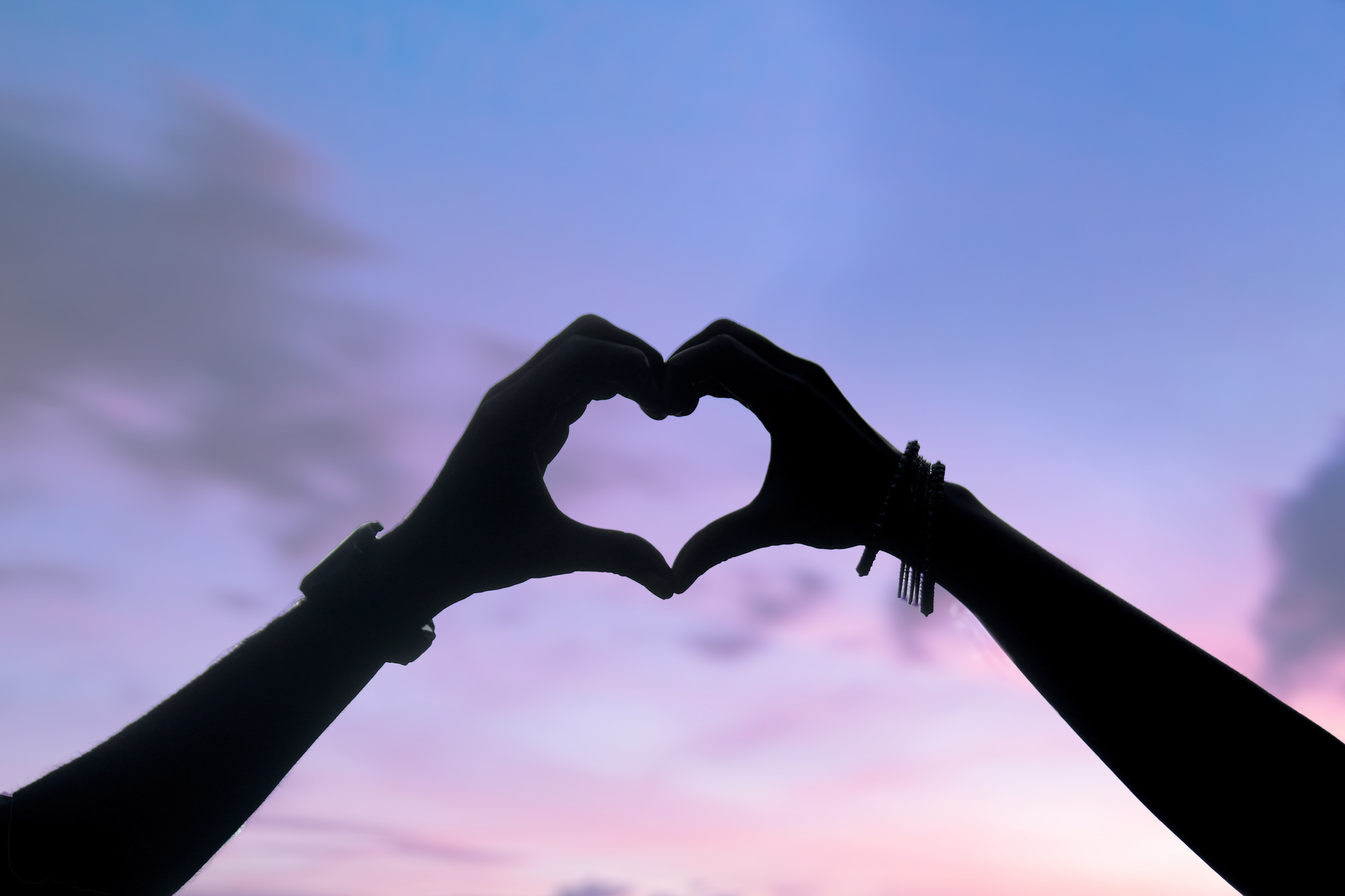 Silhouette,Cropped hands making heart shape against sky during sunset