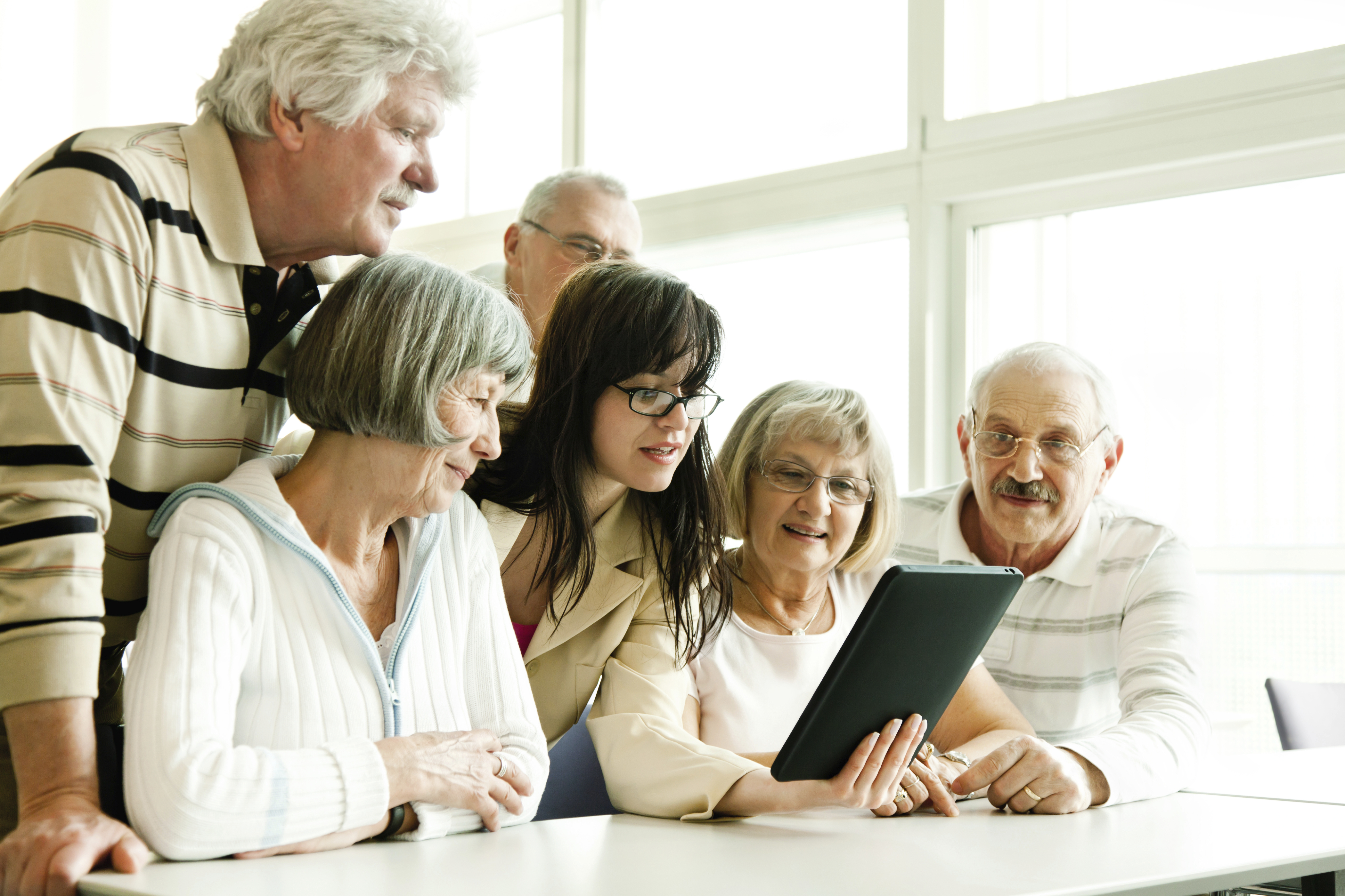 group of seniors at lecture examine tablet pc