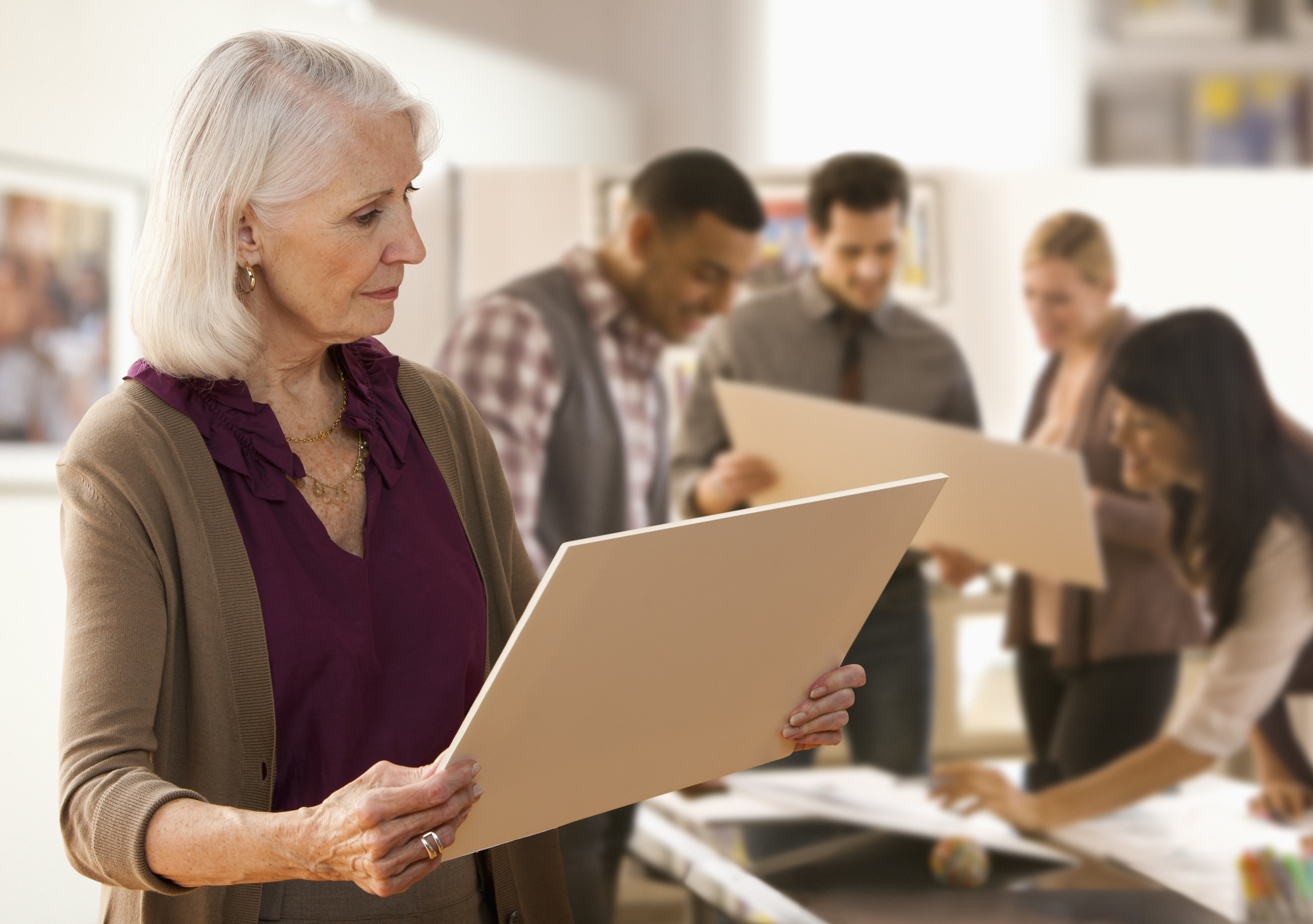 Senior woman looking at designs with colleagues