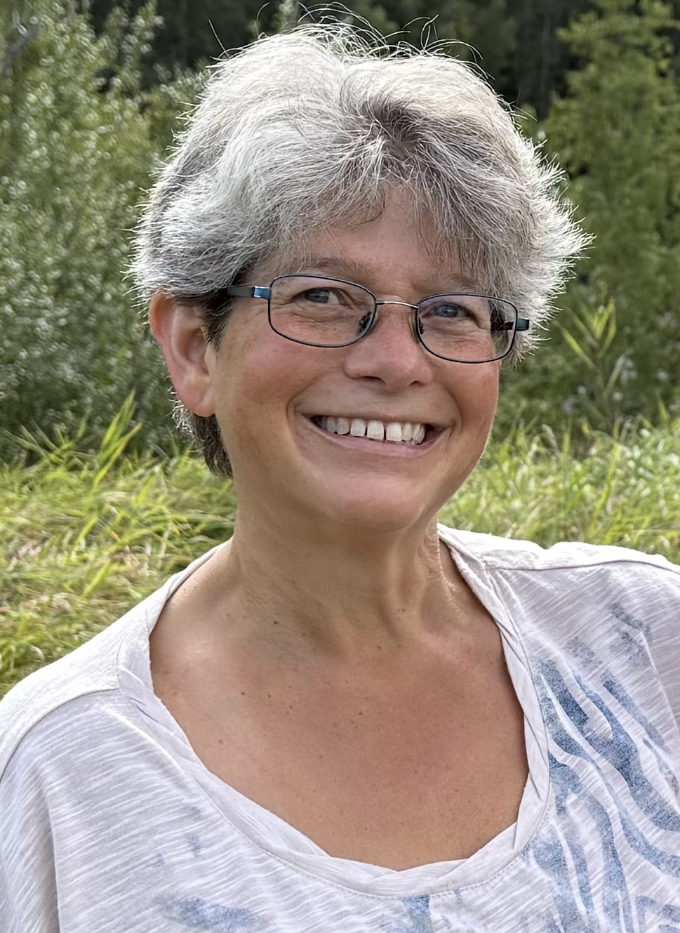 A smiling woman stands outside
