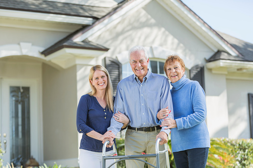 Woman with elderly parents standing in front of house