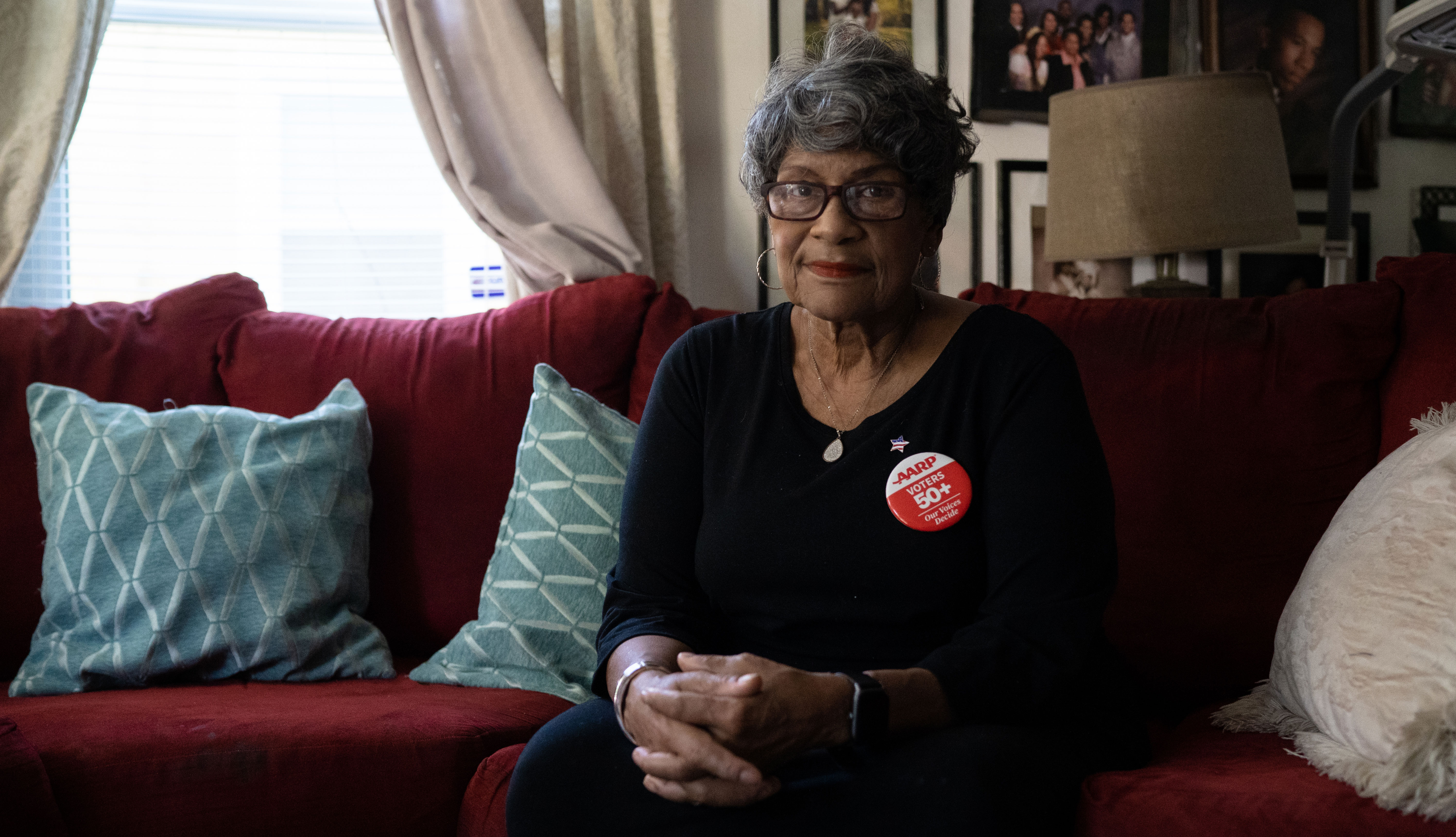 Older woman sits on her couch in her home  