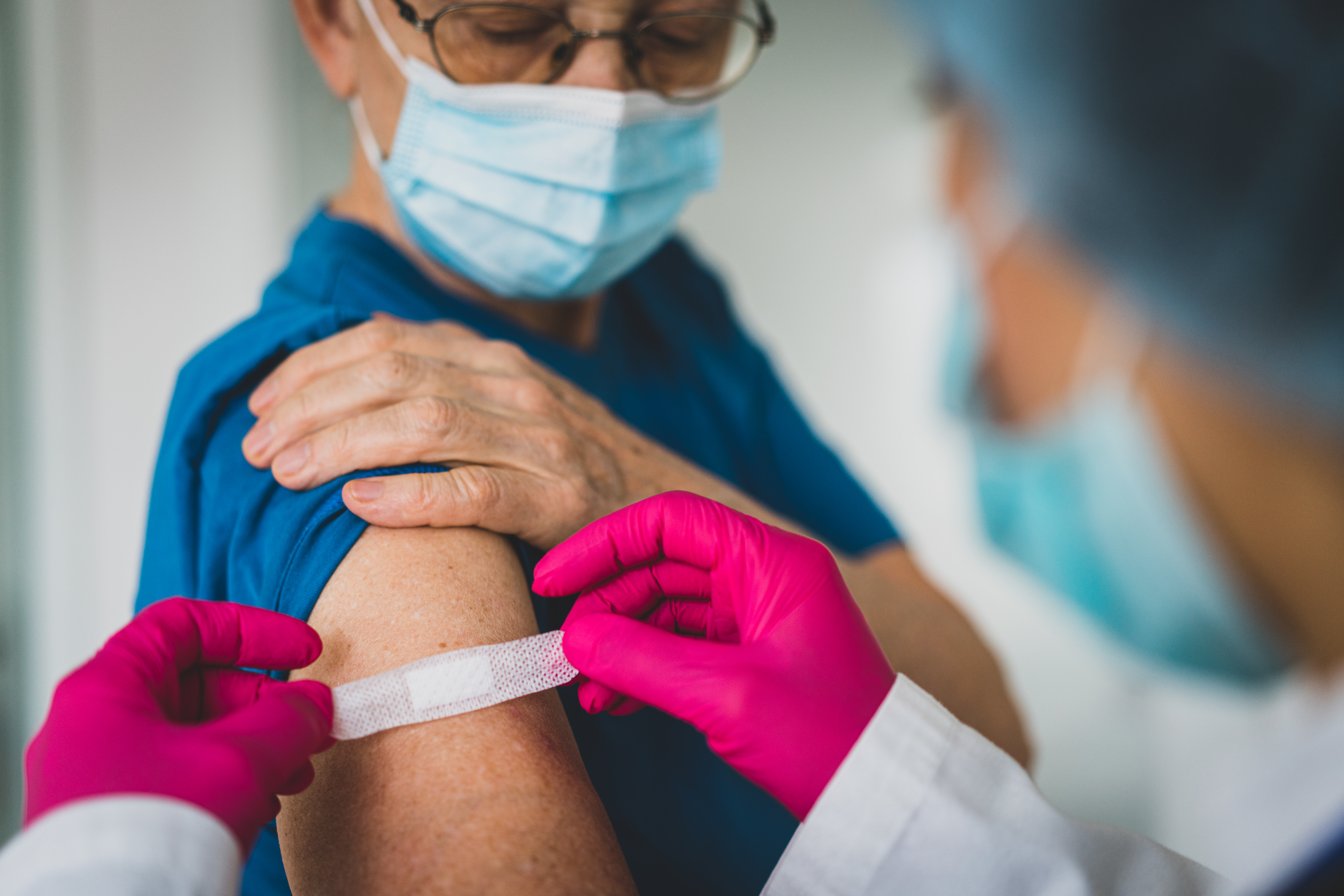 Médico coloca curita en el brazo de una mujer mayor después de vacunarla