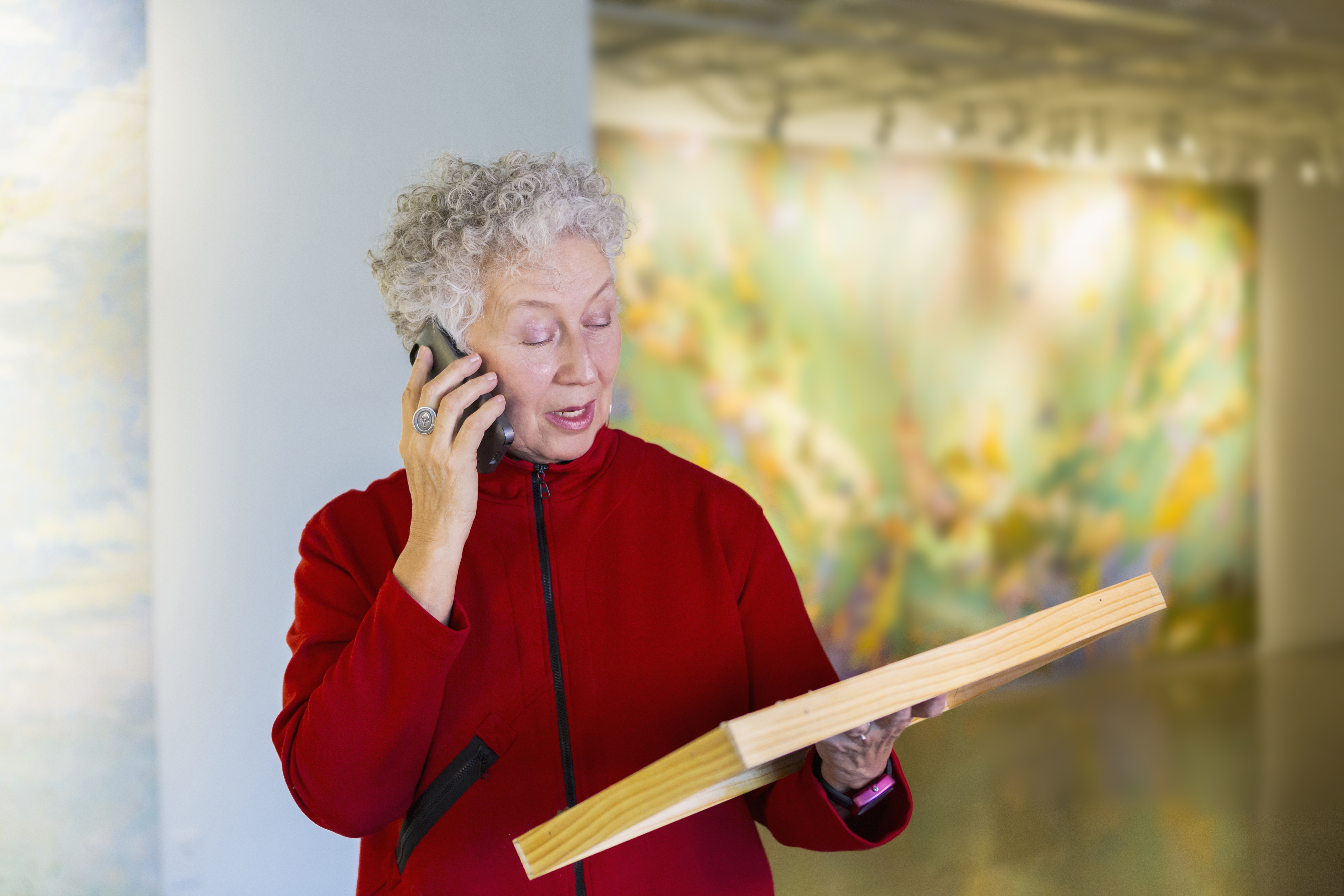 Older mixed race woman talking on phone in art gallery