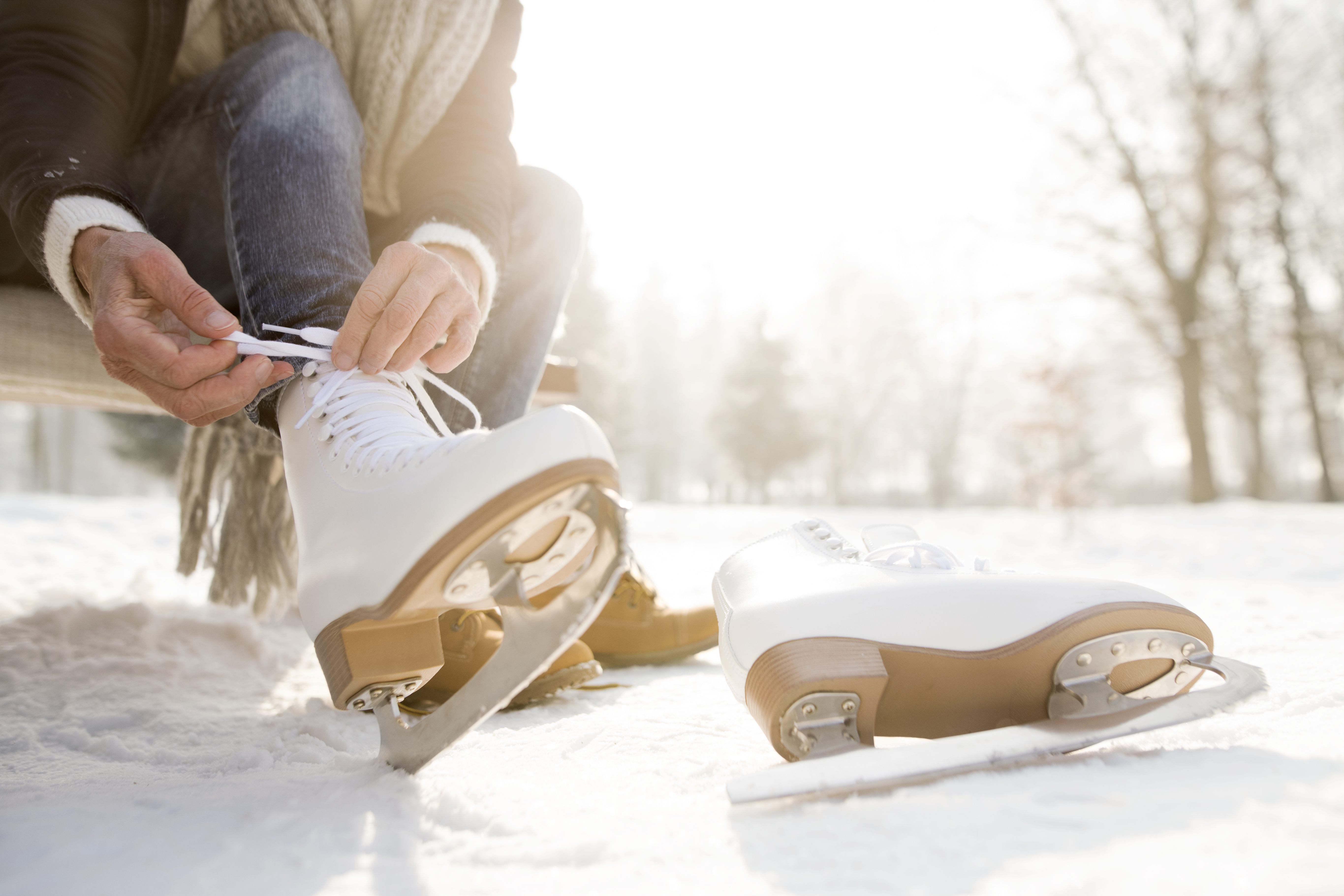 Woman sitting on bench in winter putting on ice skates