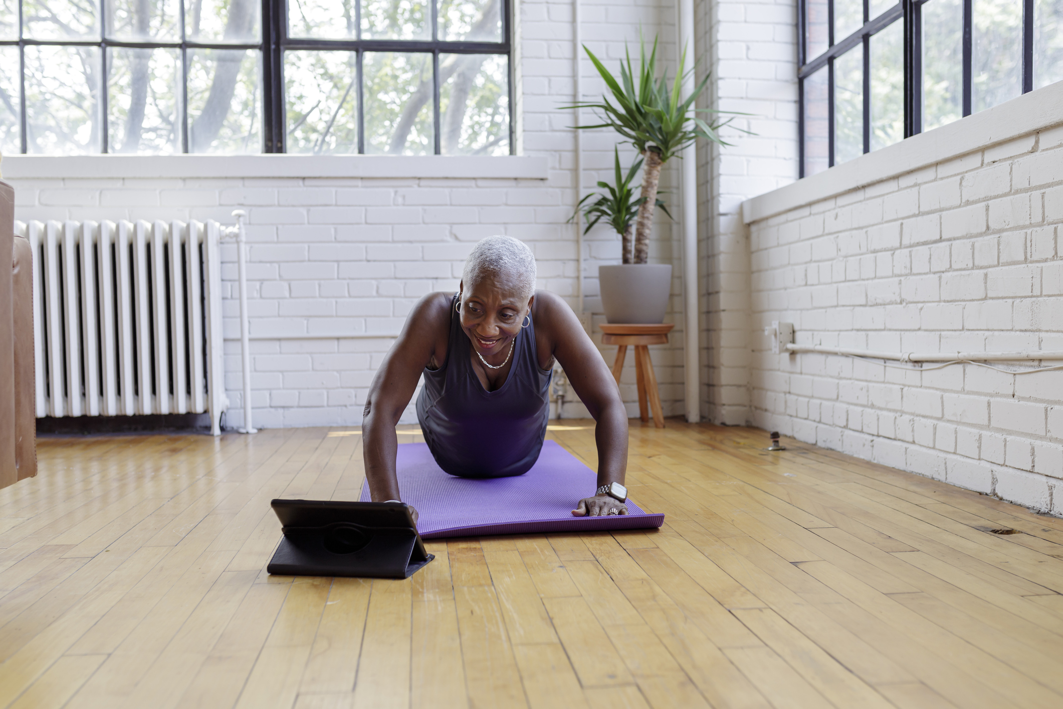 Fit senior woman taking online yoga fitness class at home