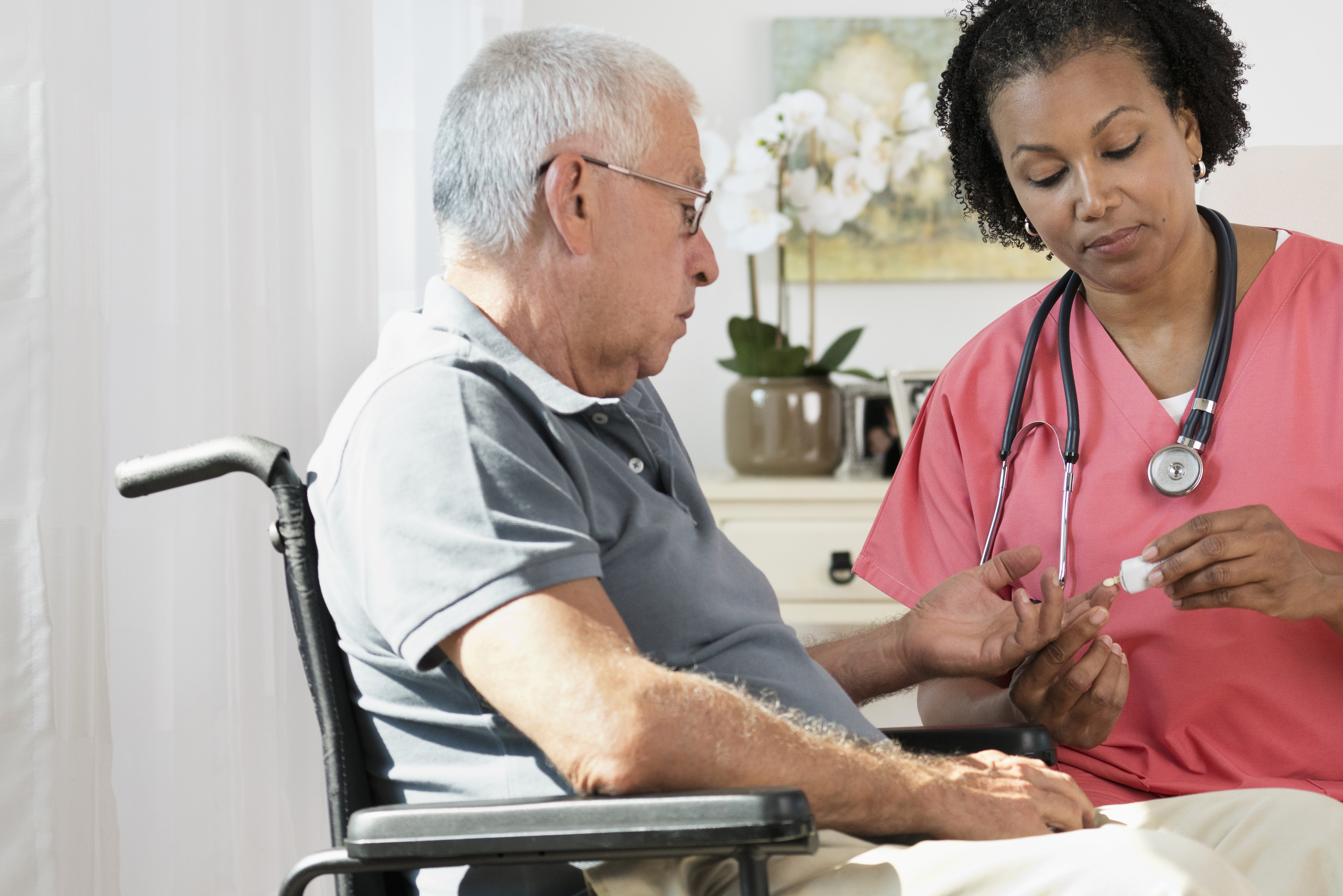 Nurse checking blood glucose of patient in wheelchair