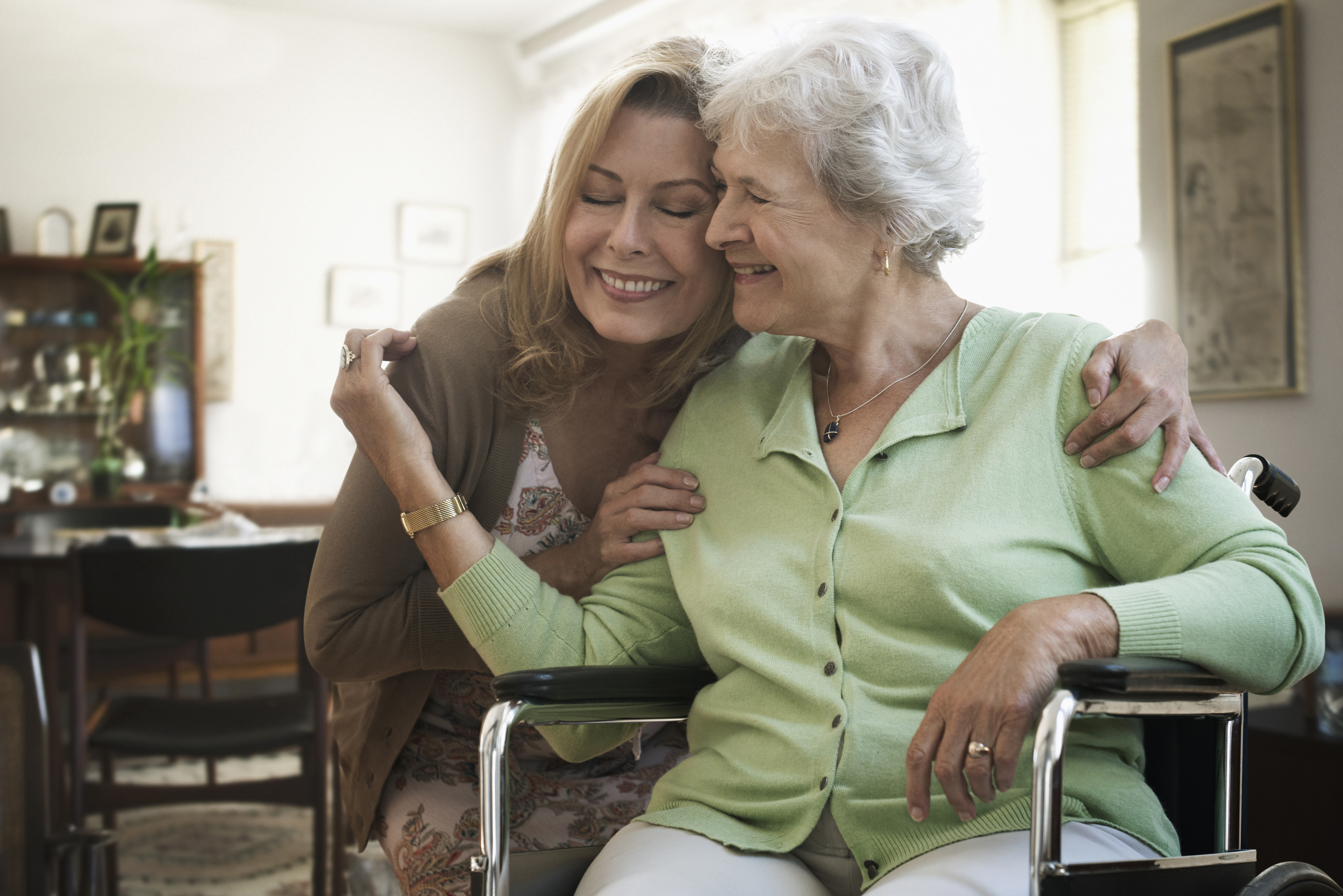 Caucasian woman hugging mother in wheelchair