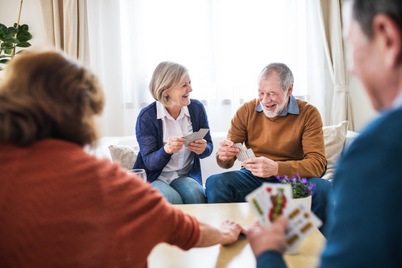 Two senior couples playing a game of cards at home.